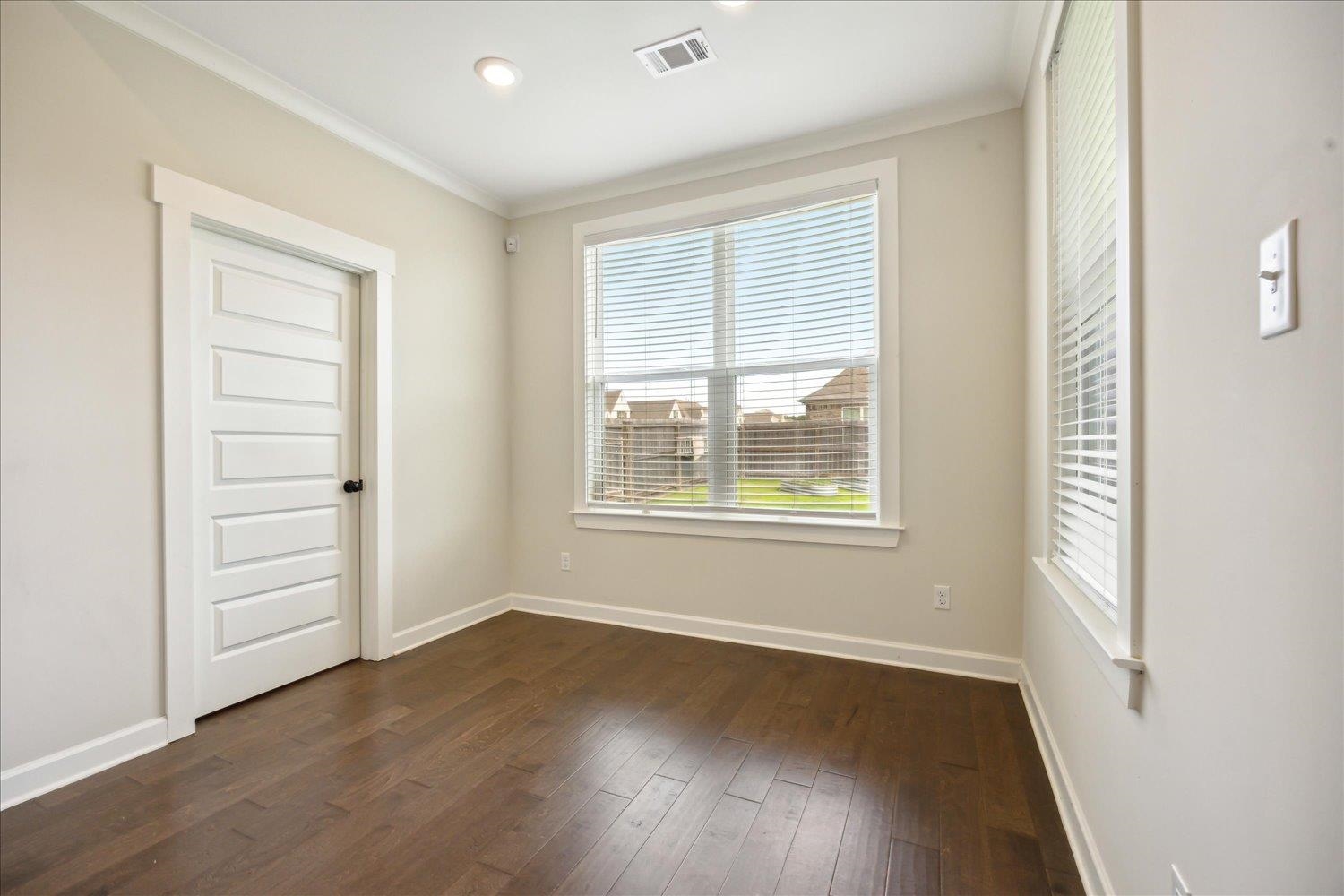 Empty room featuring crown molding and dark hardwood / wood-style floors