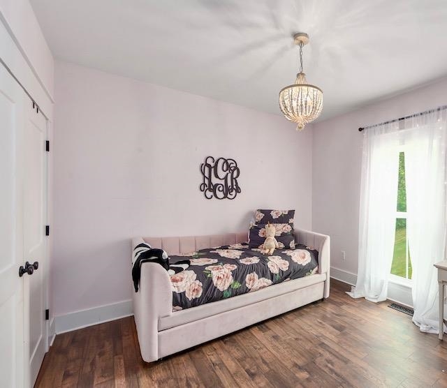 Bedroom with multiple windows, a chandelier, and dark hardwood / wood-style flooring