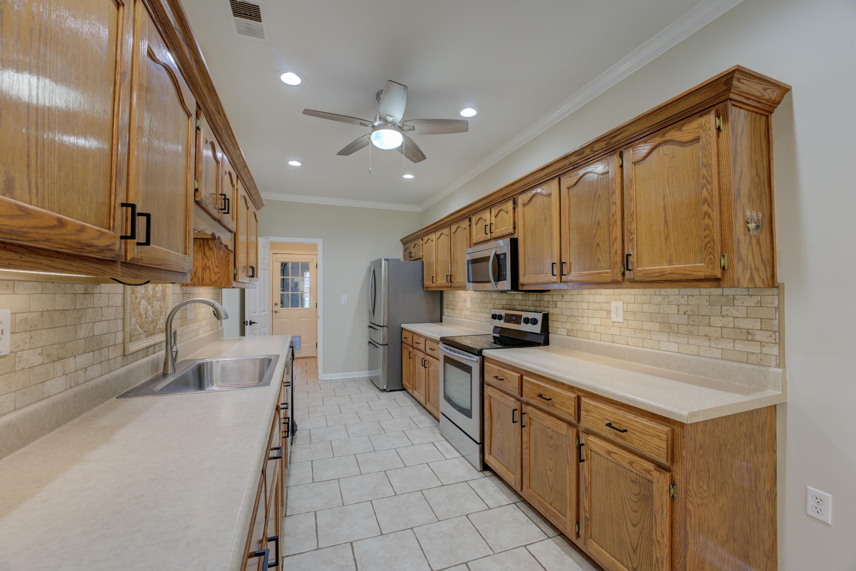 Kitchen with ornamental molding, sink, ceiling fan, decorative backsplash, and appliances with stainless steel finishes