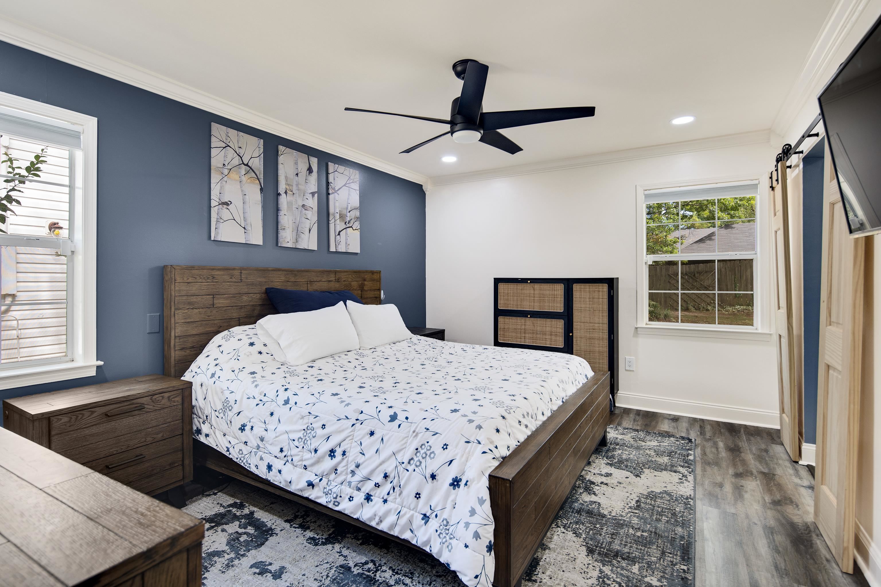 Bedroom featuring a barn door, ceiling fan, ornamental molding, and hardwood / wood-style floors