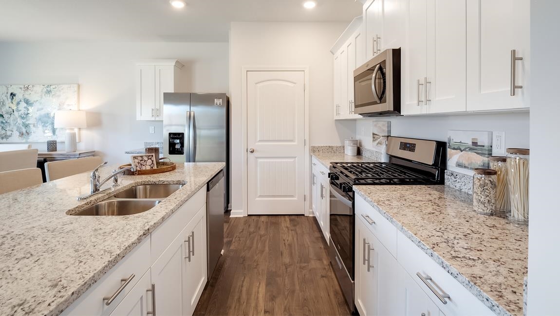 Kitchen featuring appliances with stainless steel finishes, sink, white cabinets, and dark wood-type flooring