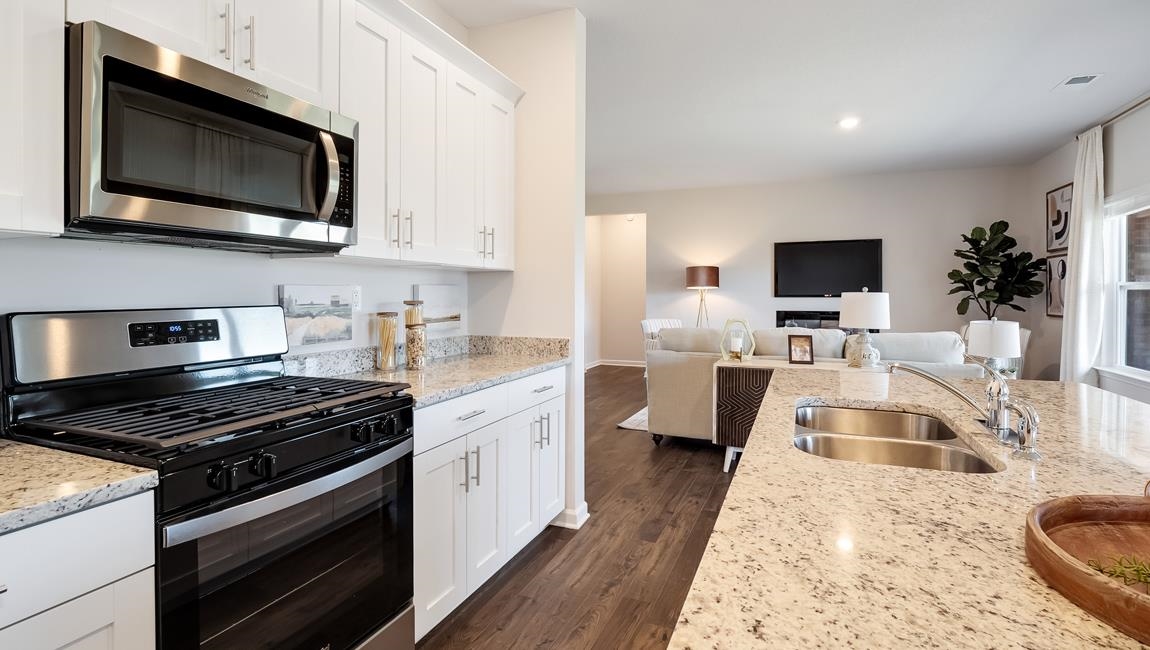 Kitchen featuring white cabinetry, stainless steel appliances, dark hardwood / wood-style flooring, light stone counters, and sink