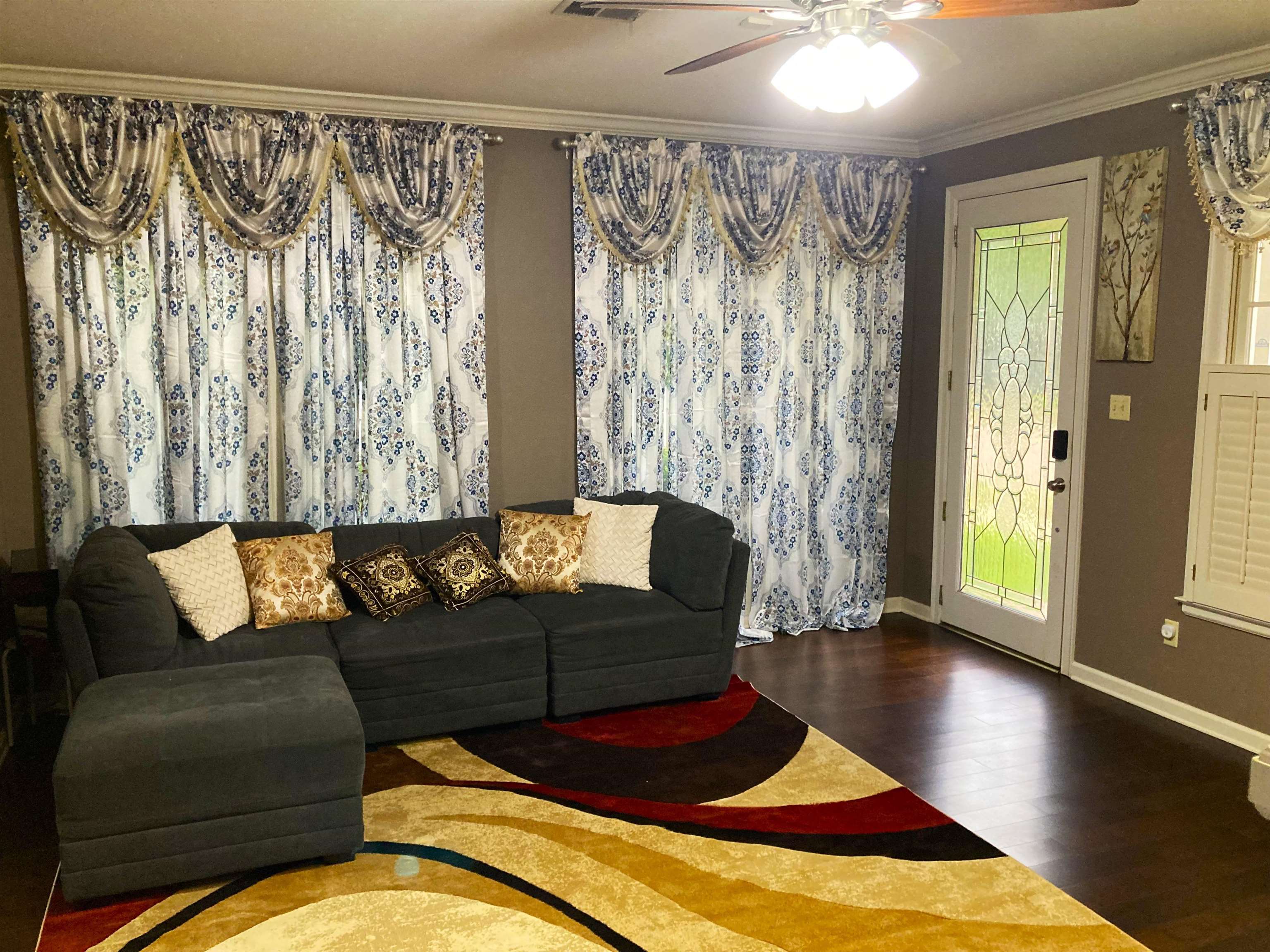 Living room with hardwood / wood-style floors, ceiling fan, a wealth of natural light, and ornamental molding