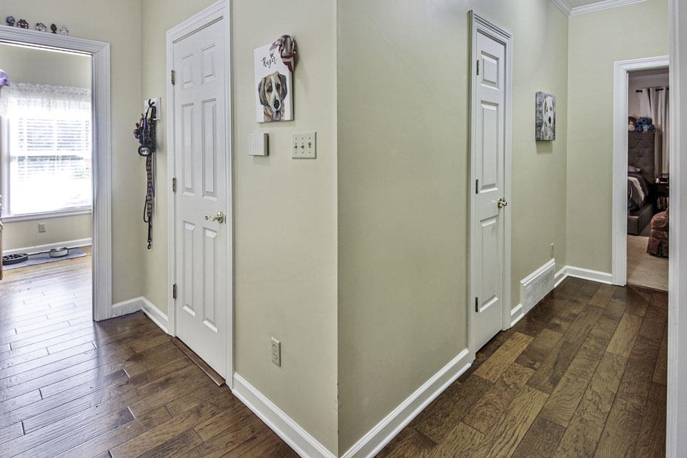 Hall with dark hardwood / wood-style floors and crown molding