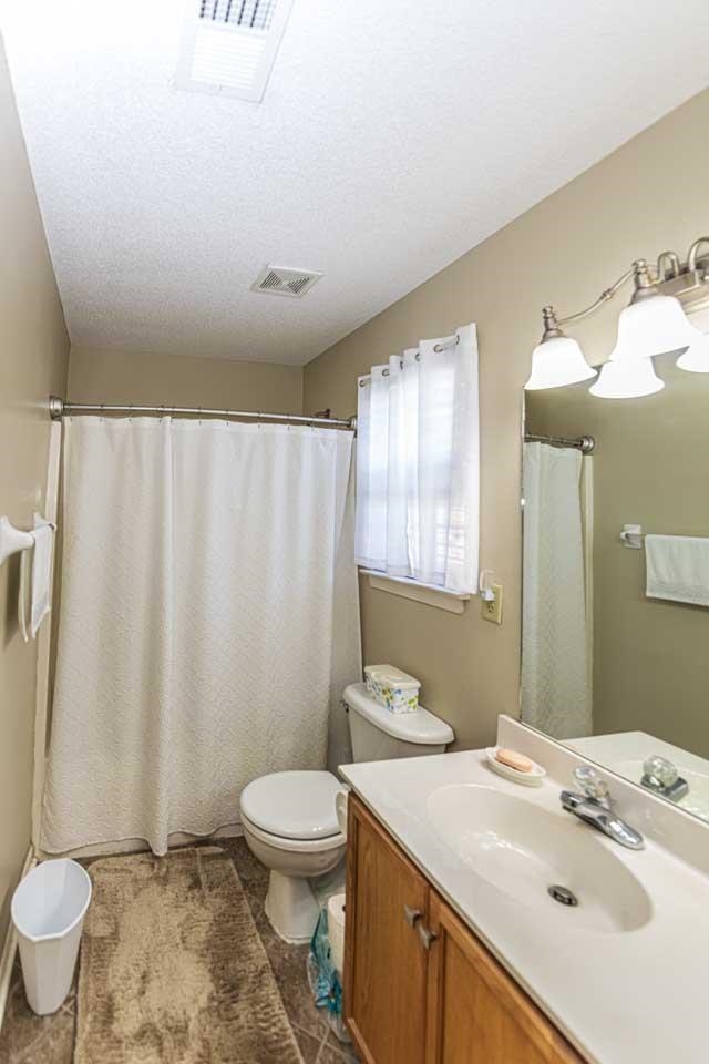 Bathroom with vanity, toilet, curtained shower, and a textured ceiling