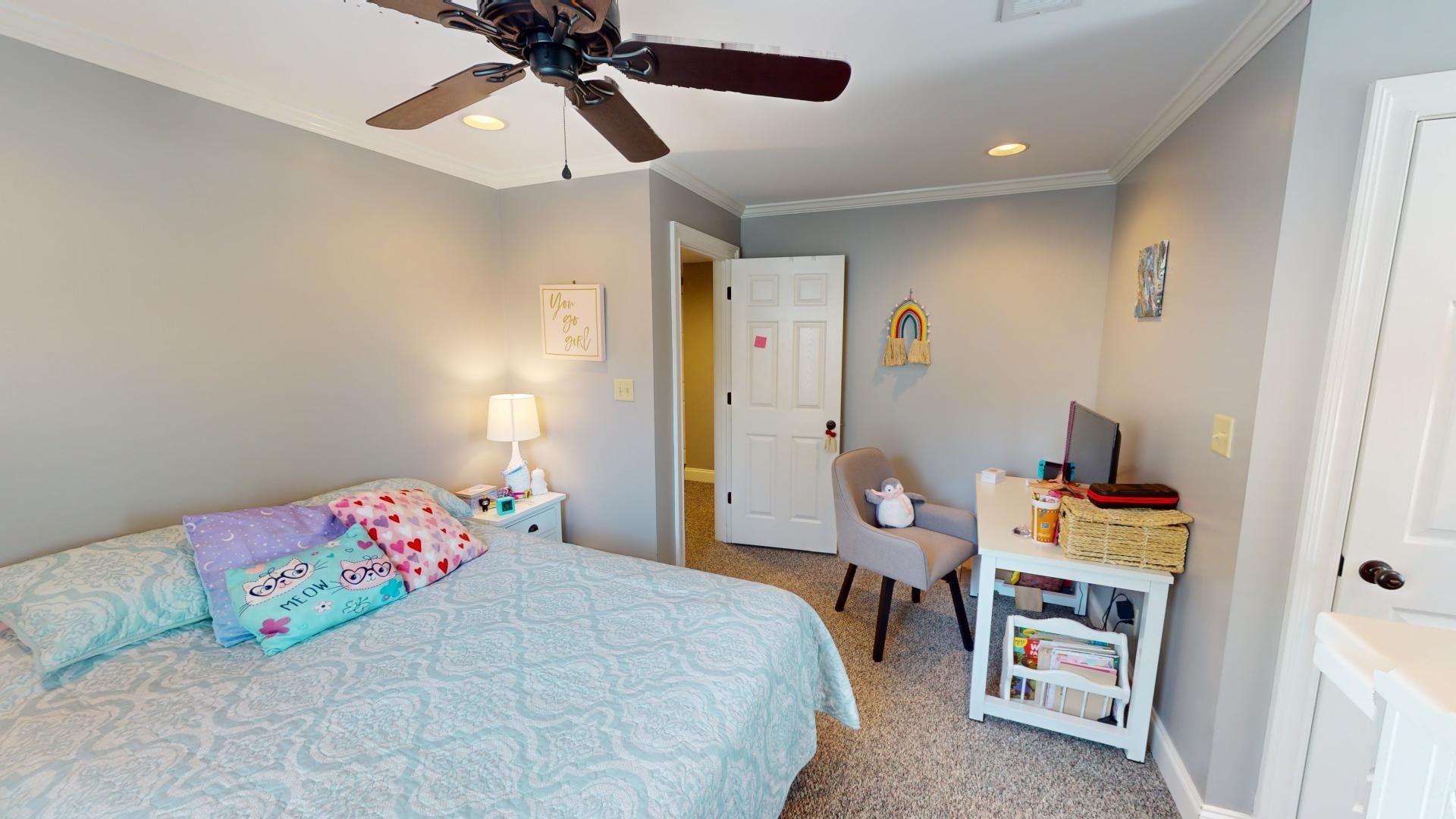 Carpeted bedroom featuring ceiling fan and crown molding