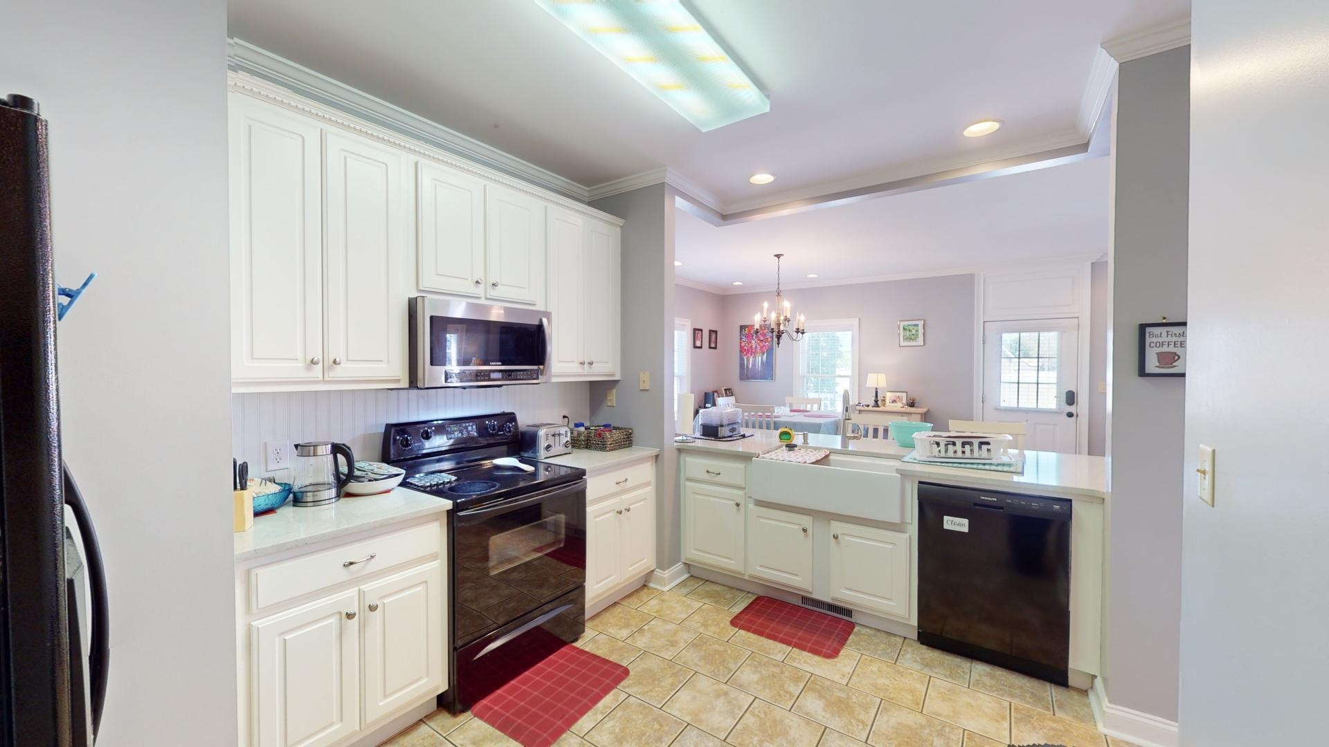 Kitchen featuring ornamental molding, decorative light fixtures, black appliances, kitchen peninsula, and an inviting chandelier