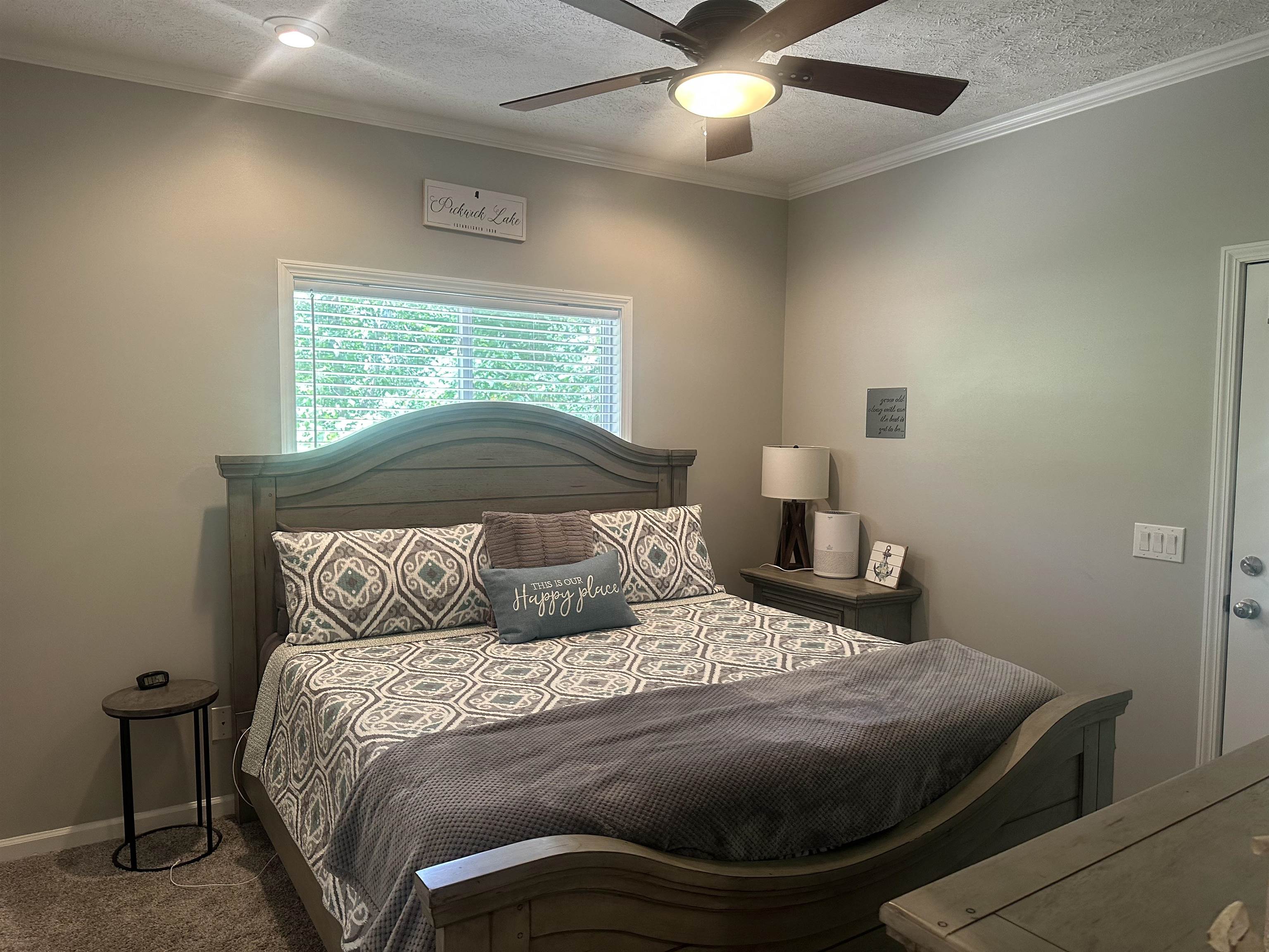 Carpeted bedroom with ceiling fan, ornamental molding, and a textured ceiling