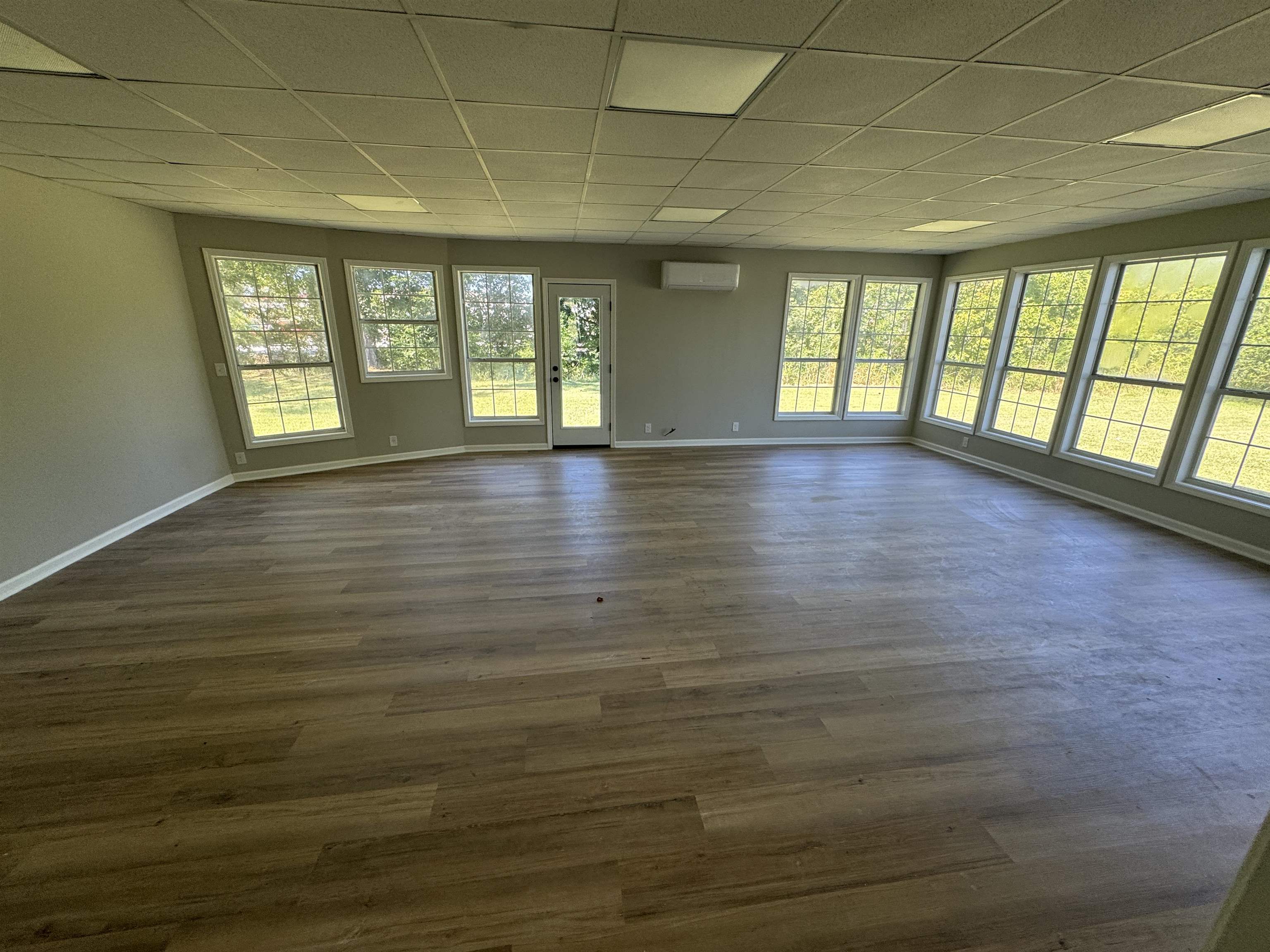 Unfurnished room with plenty of natural light, dark hardwood / wood-style flooring, and a drop ceiling