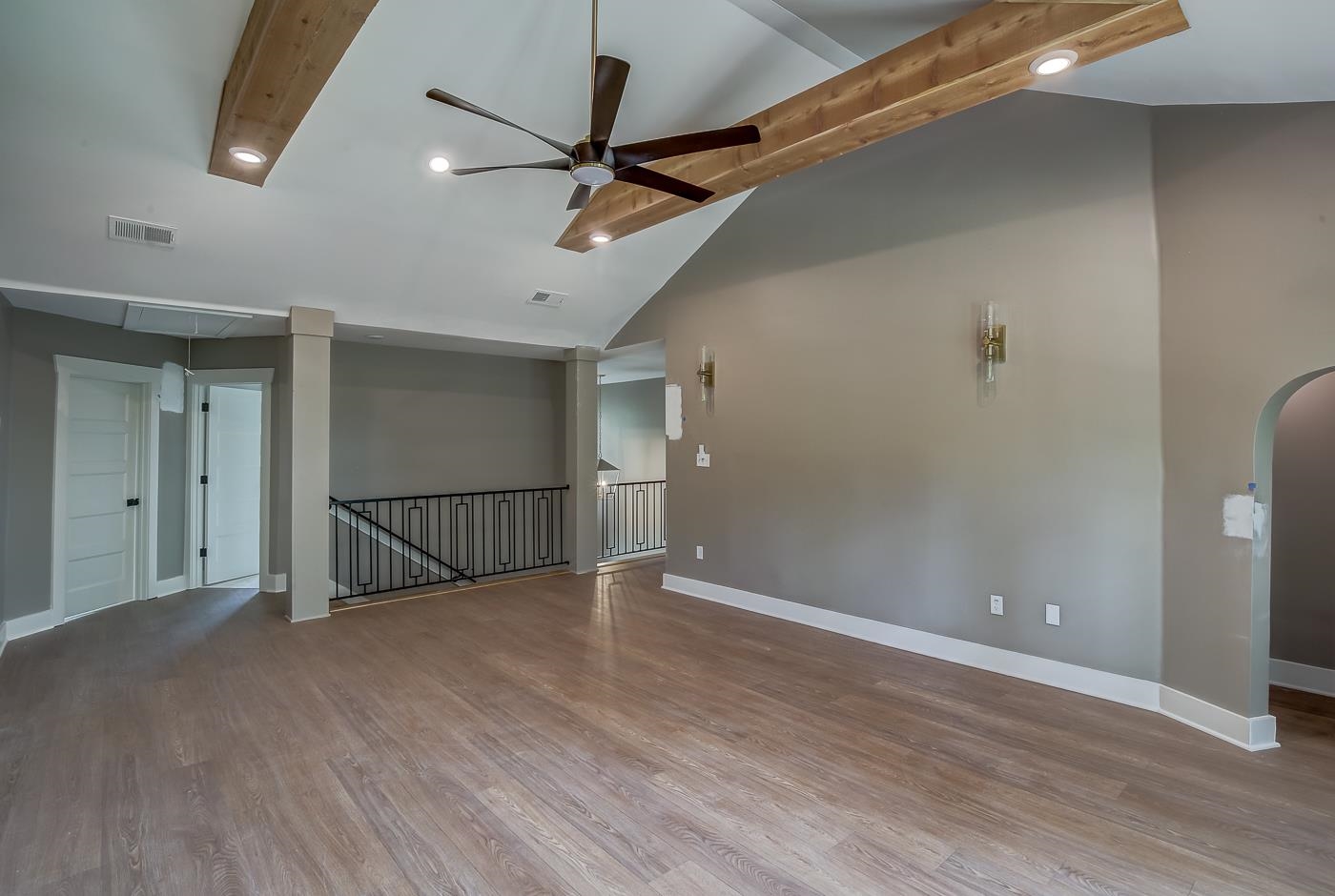 Unfurnished room with high vaulted ceiling, hardwood / wood-style flooring, beam ceiling, and ceiling fan