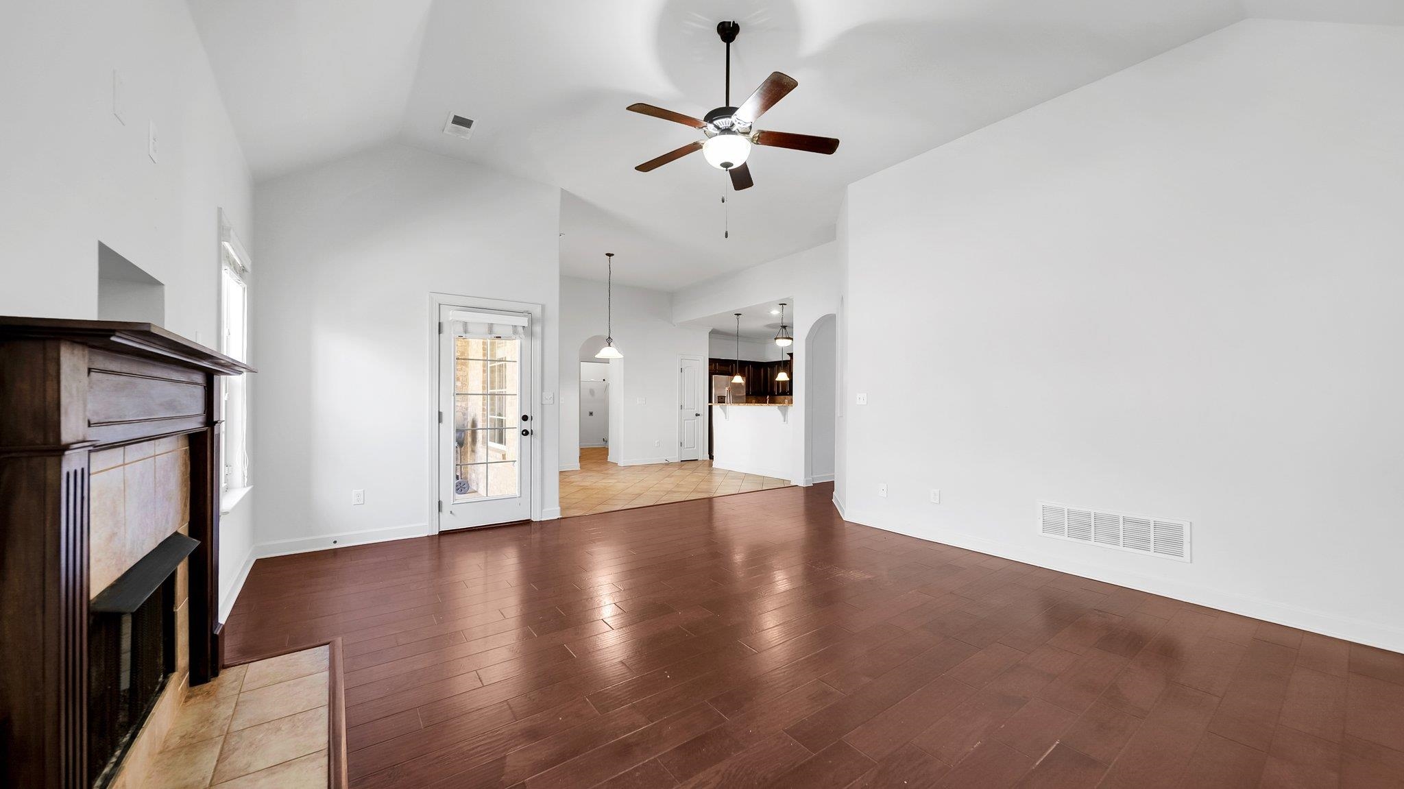 Unfurnished living room featuring a fireplace, high vaulted ceiling, wood-type flooring, and ceiling fan