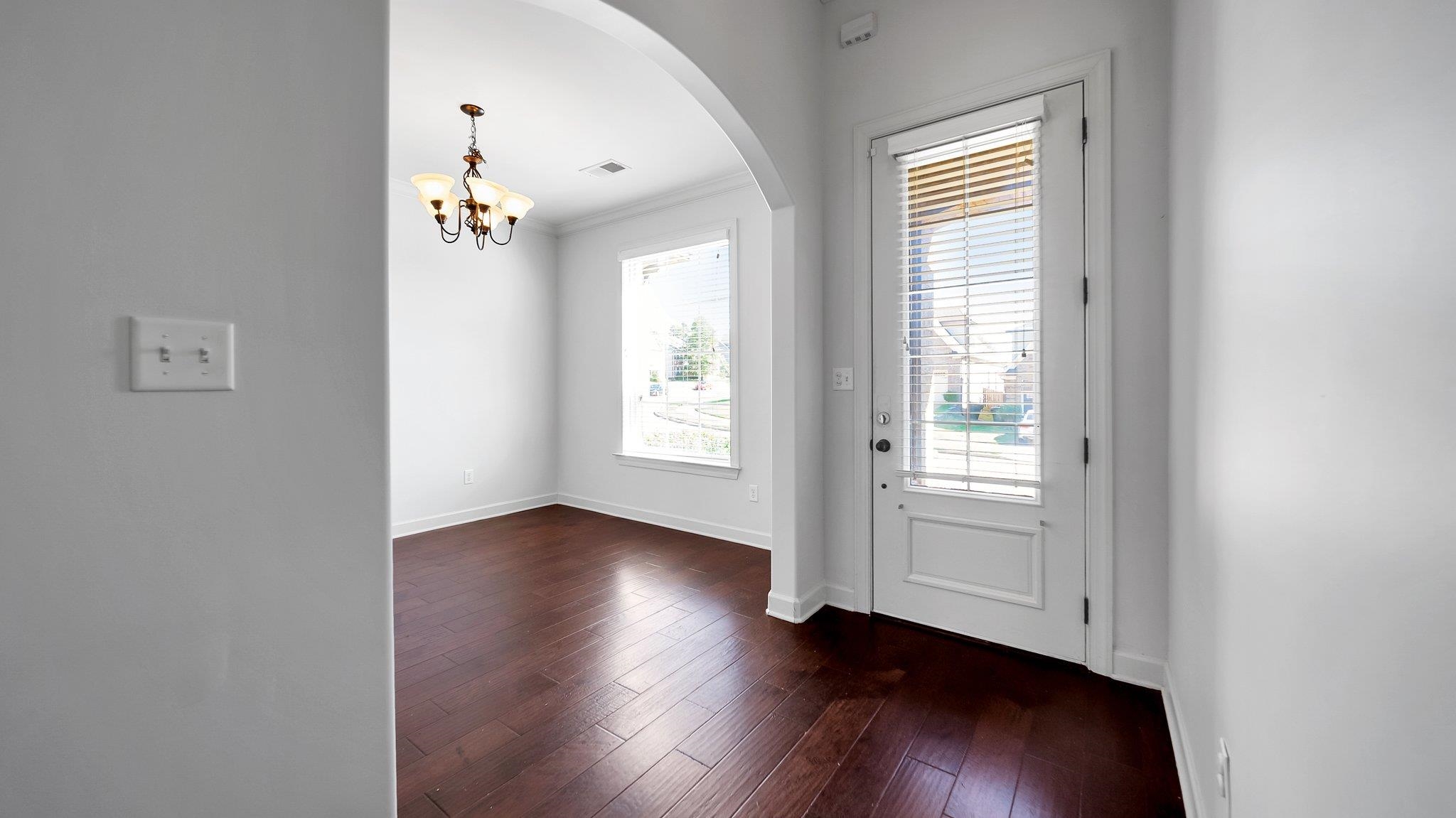 Entrance foyer featuring crown molding, dark hardwood / wood-style floors, and a chandelier