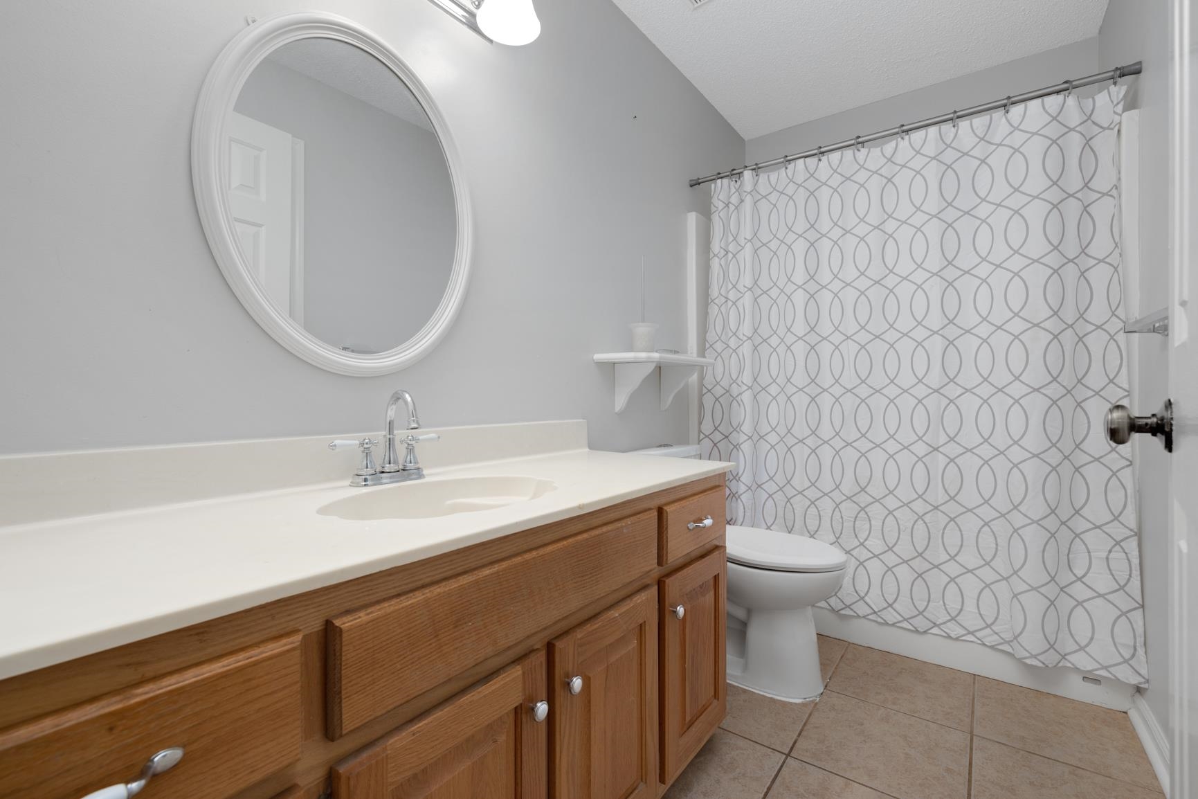 Bathroom featuring tile patterned flooring, toilet, walk in shower, and vanity