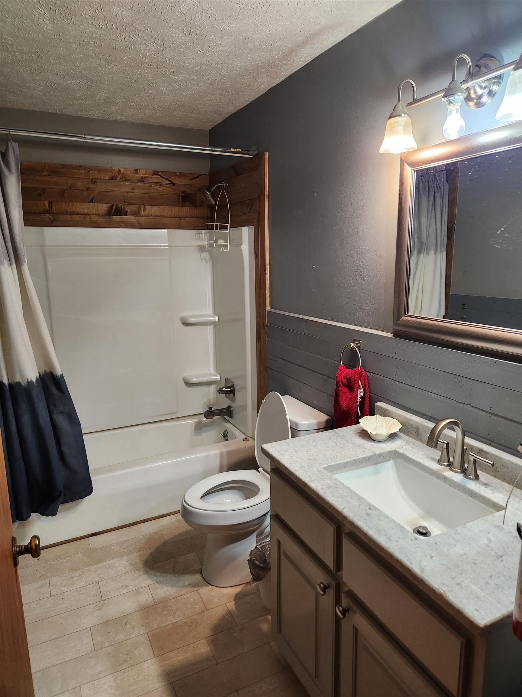 Full bathroom with toilet, vanity, hardwood / wood-style flooring, a textured ceiling, and shower / tub combo