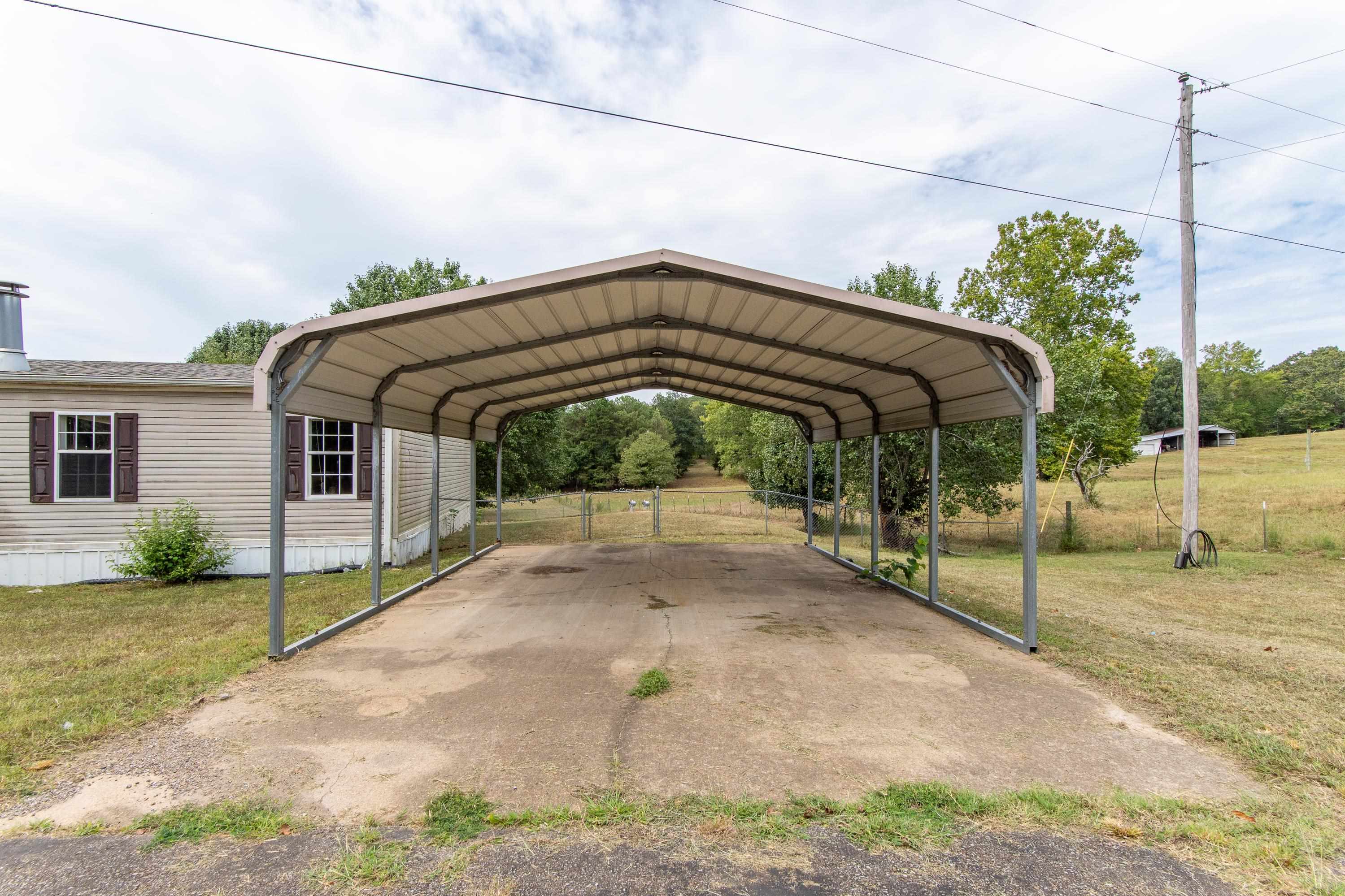 View of parking featuring a lawn and a carport