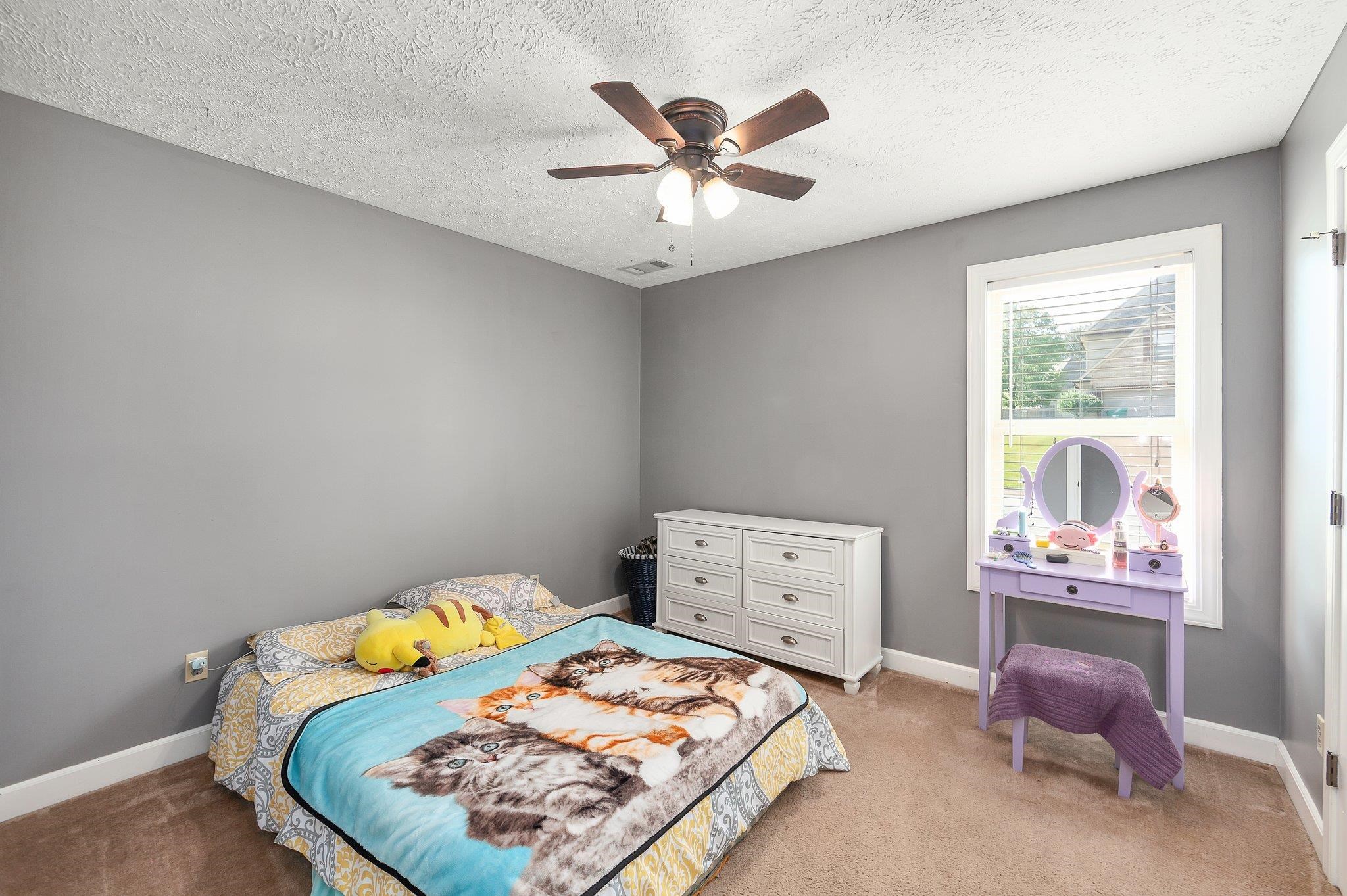 Carpeted bedroom with ceiling fan and a textured ceiling