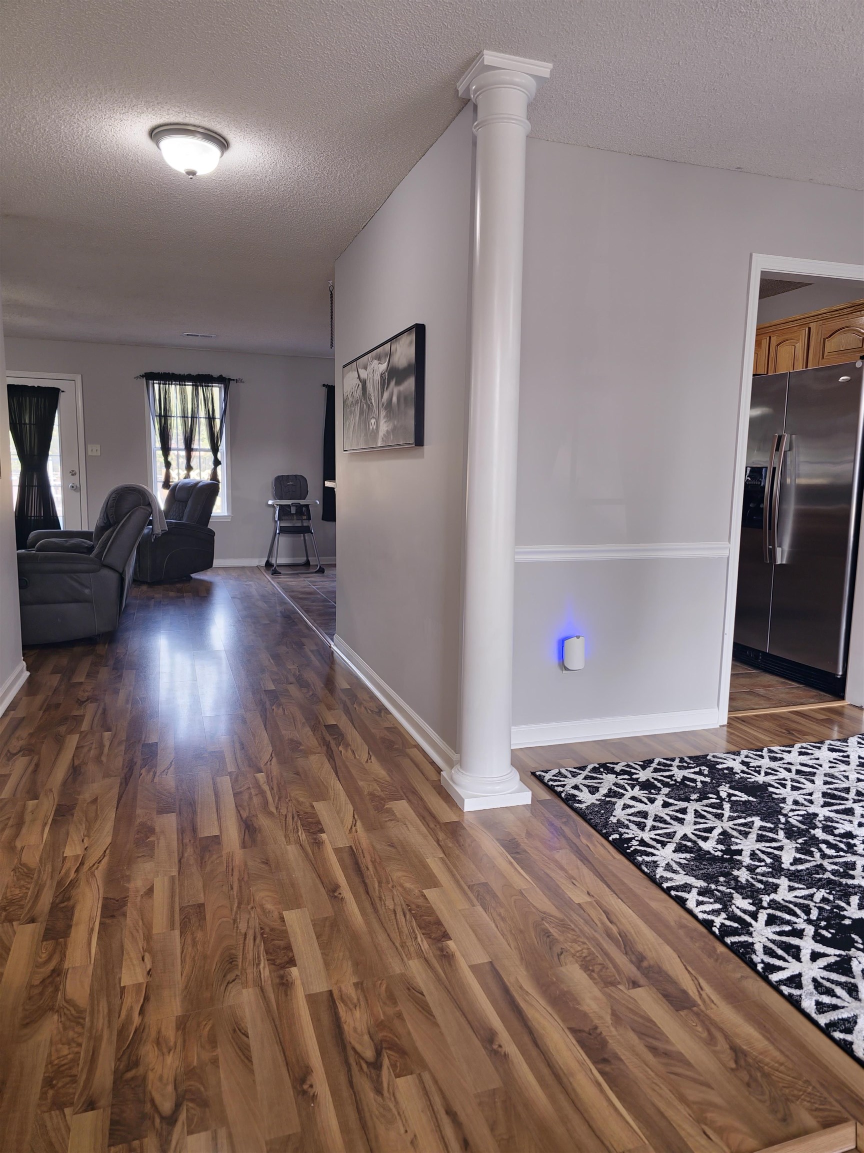 Corridor with decorative columns, dark hardwood / wood-style flooring, and a textured ceiling