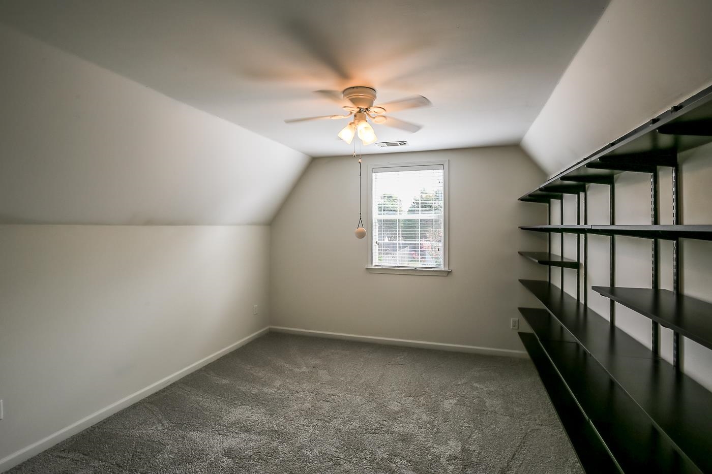 Additional living space with lofted ceiling, ceiling fan, and dark colored carpet