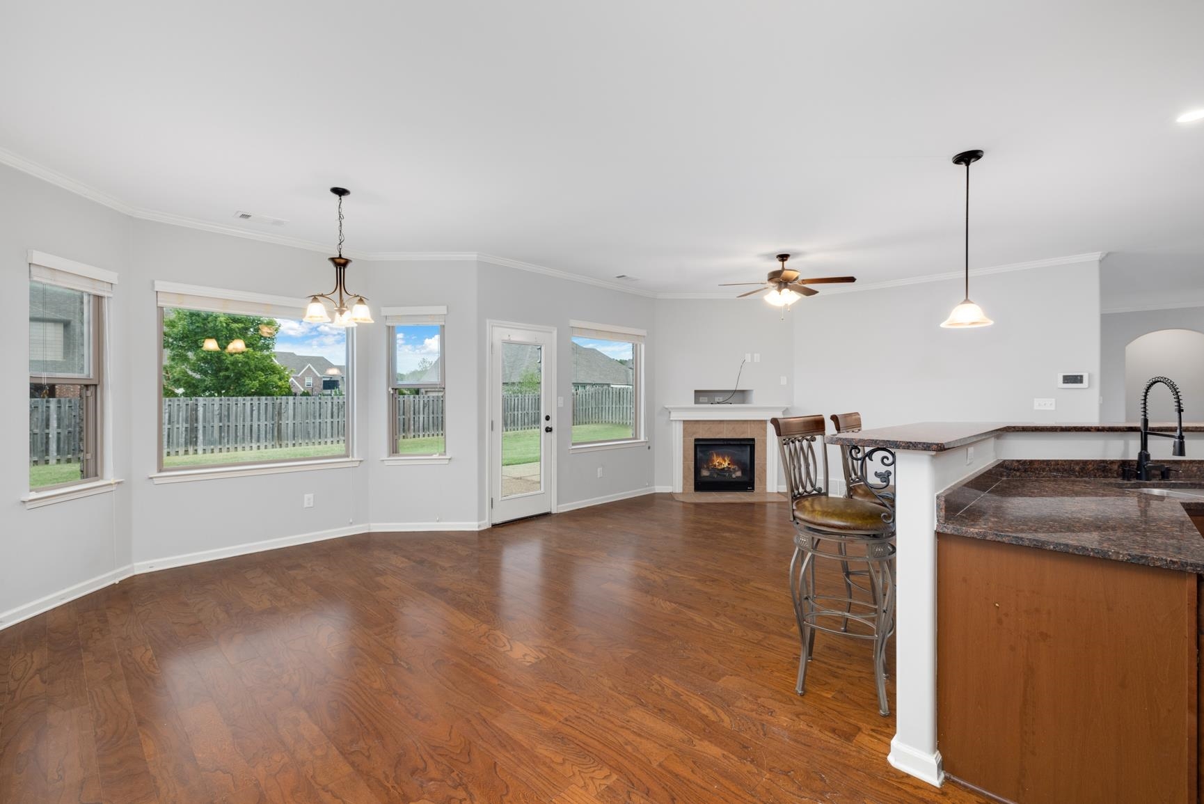 Kitchen with ceiling fan with notable chandelier, crown molding, decorative light fixtures, dark hardwood / wood-style floors, and a breakfast bar area