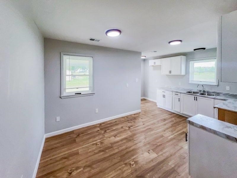 Kitchen with white cabinets, light hardwood / wood-style floors, and sink