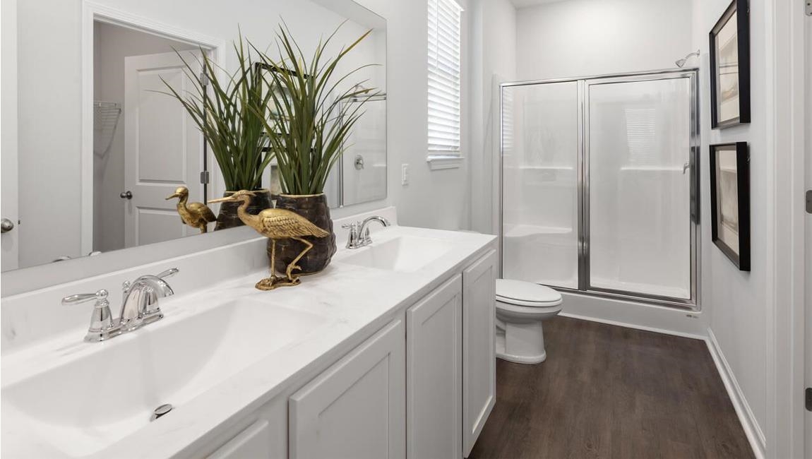 Bathroom with dual vanity, a shower with door, toilet, and hardwood / wood-style floors