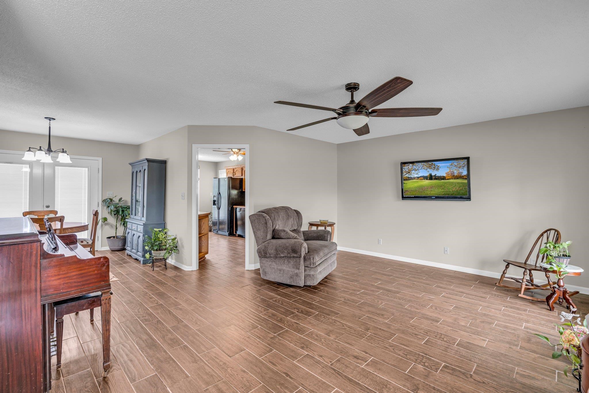 Living room featuring a textured ceiling, hardwood / wood-style floors, and ceiling fan with notable chandelier