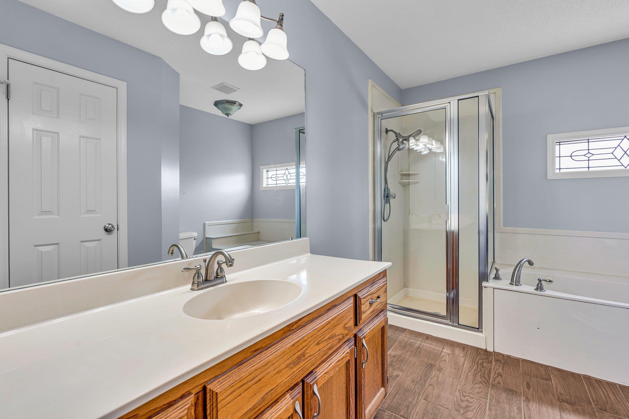 Full bathroom with vanity, toilet, hardwood / wood-style floors, and separate shower and tub