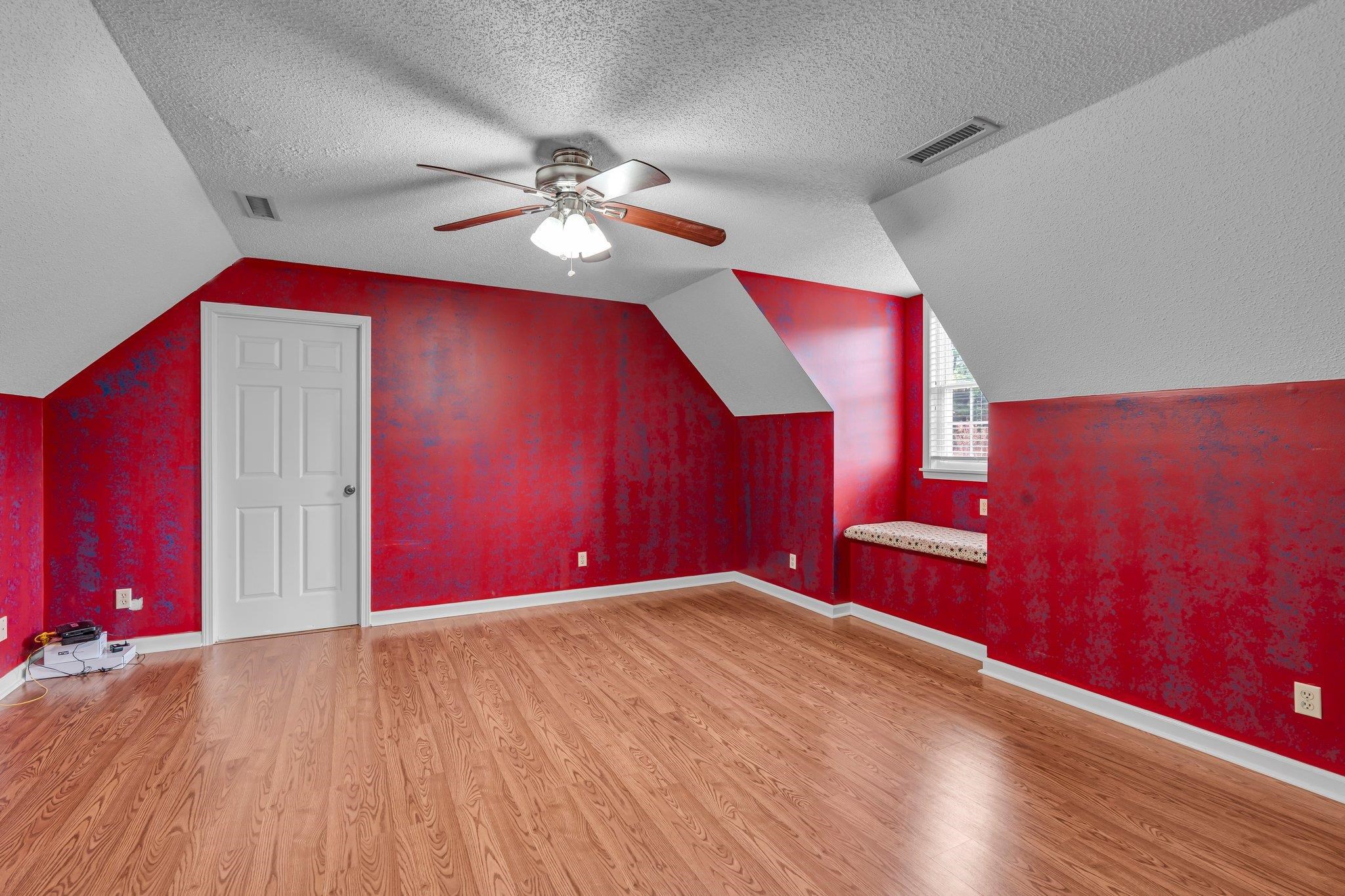 Bonus room featuring lofted ceiling, hardwood / wood-style flooring, ceiling fan, and a textured ceiling