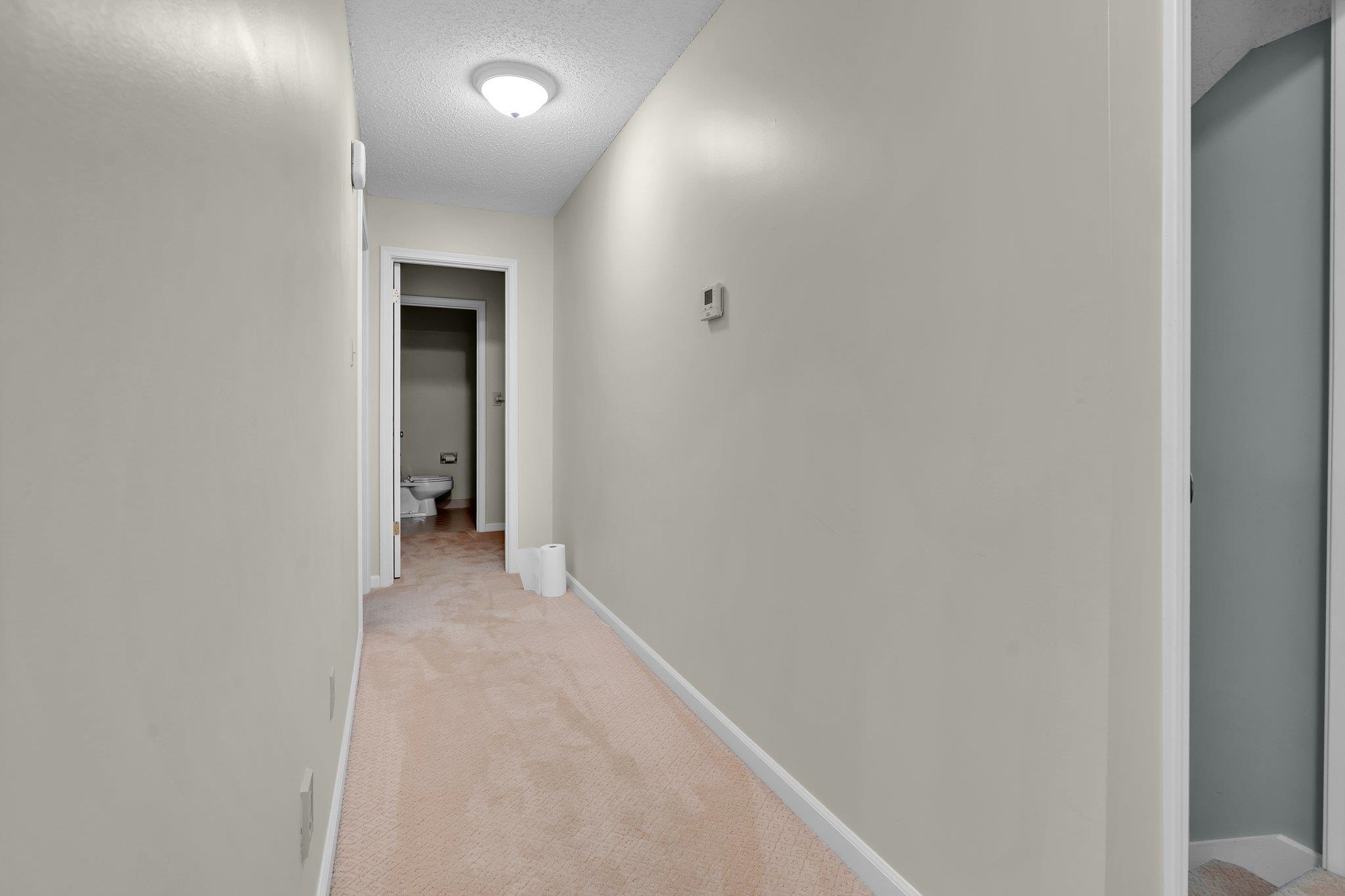 Corridor with a textured ceiling and light carpet