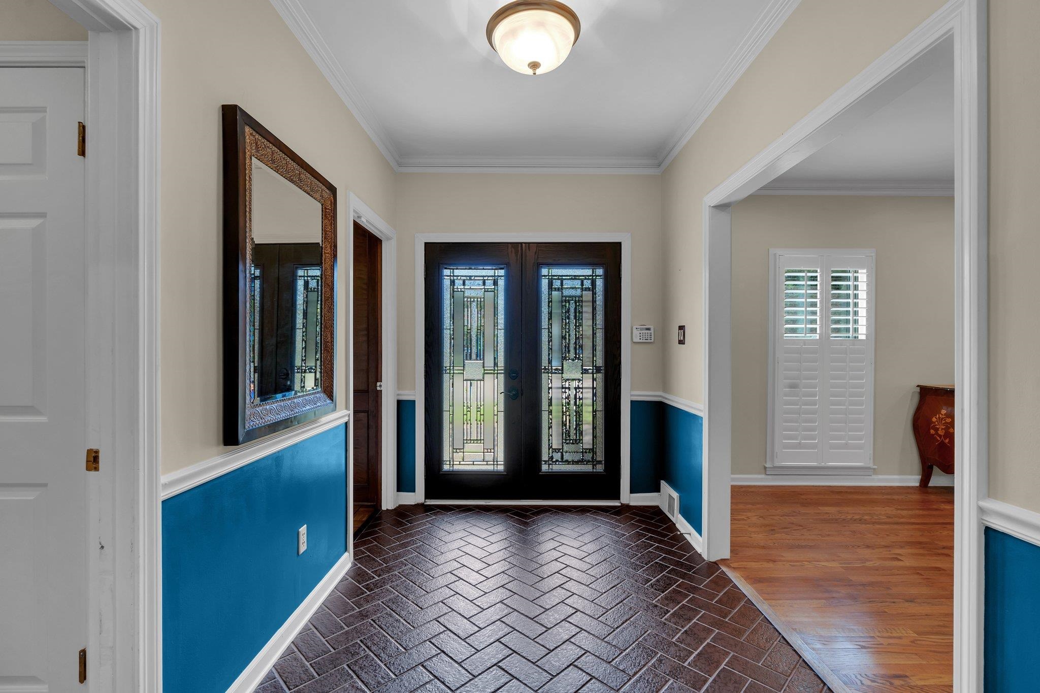 Foyer featuring dark wood-type flooring, crown molding, and french doors