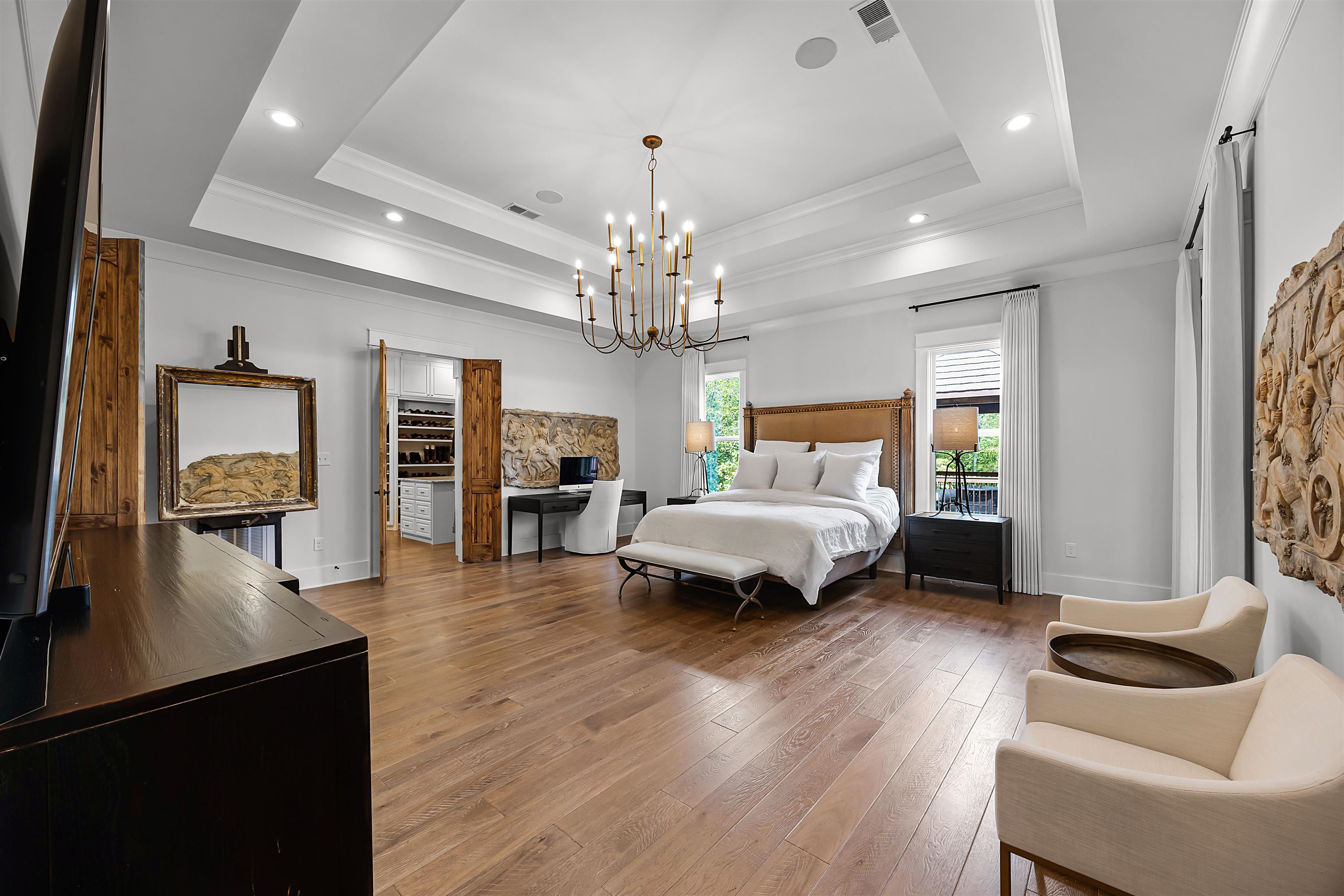 Bedroom with an inviting chandelier, hardwood / wood-style floors, a tray ceiling, ornamental molding, and a barn door