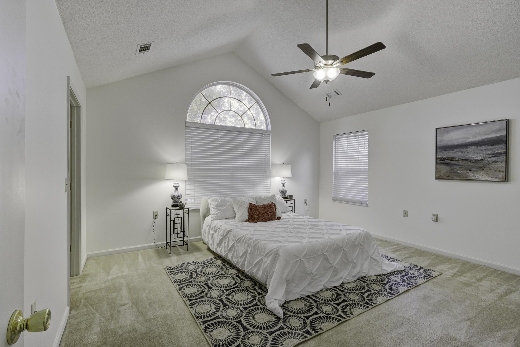 Carpeted bedroom with walk in closet, vaulted ceiling, and new ceiling fan