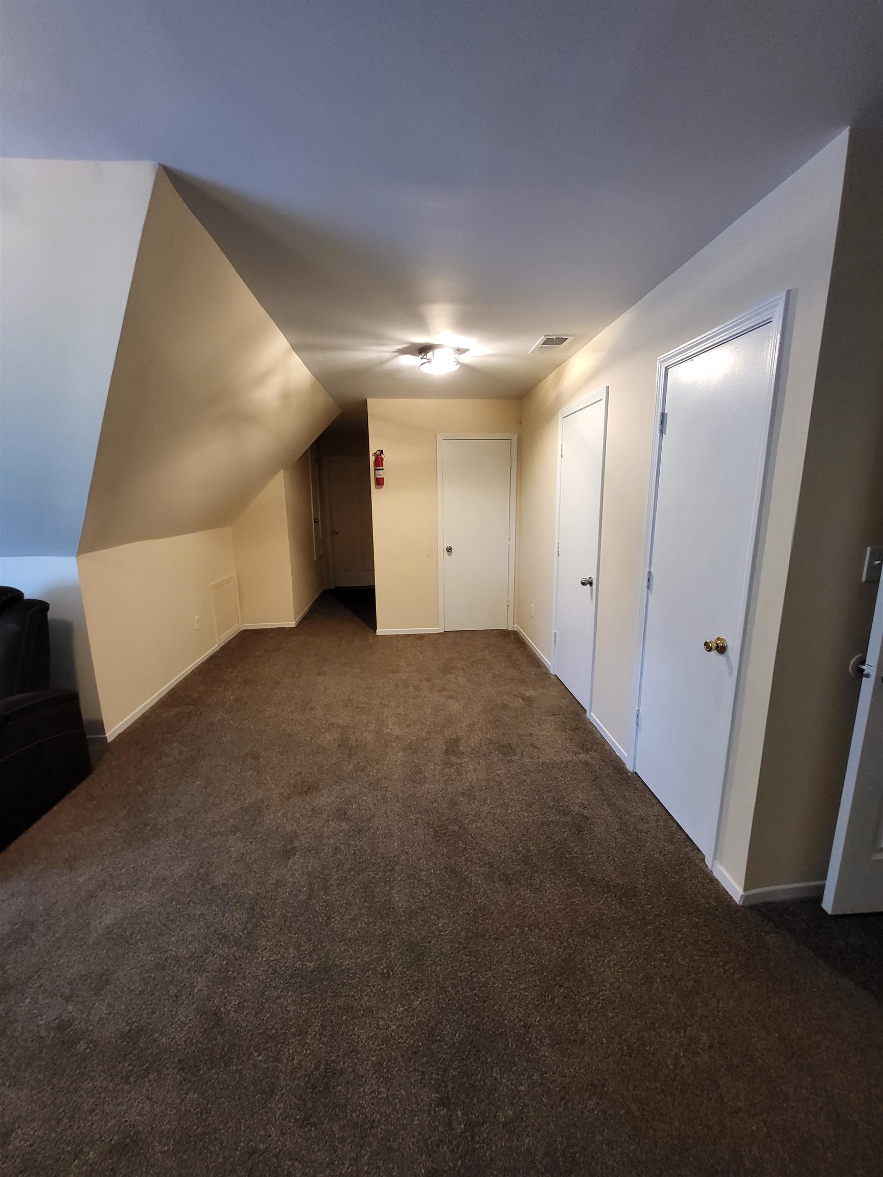 Additional living space featuring vaulted ceiling and dark carpet