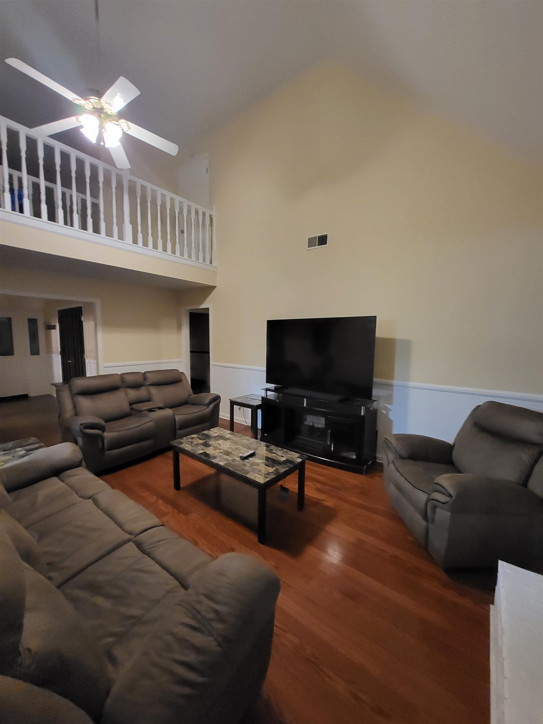 Living room featuring high vaulted ceiling, hardwood / wood-style floors, and ceiling fan