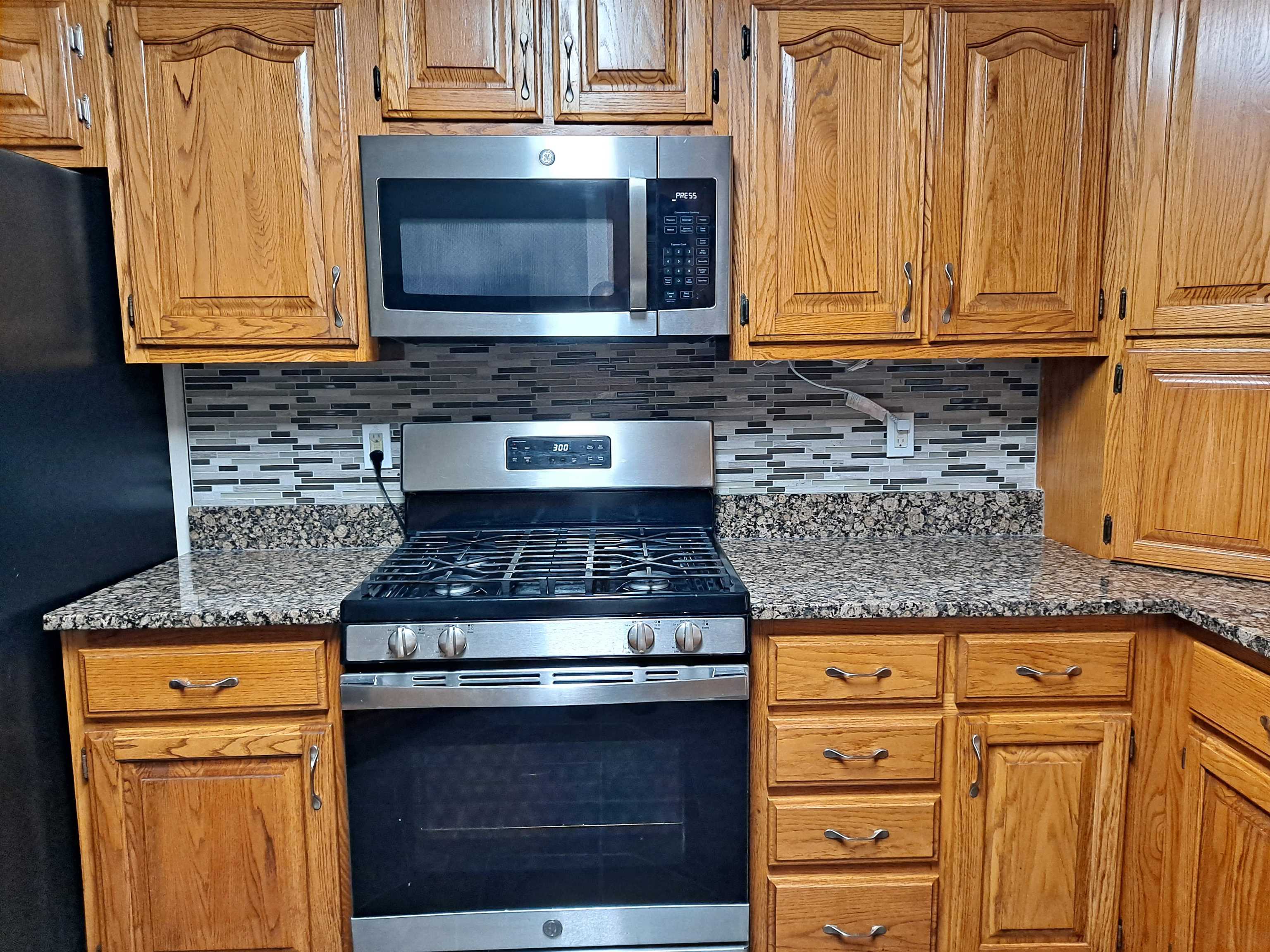 Kitchen with appliances with stainless steel finishes, dark stone counters, and tasteful backsplash