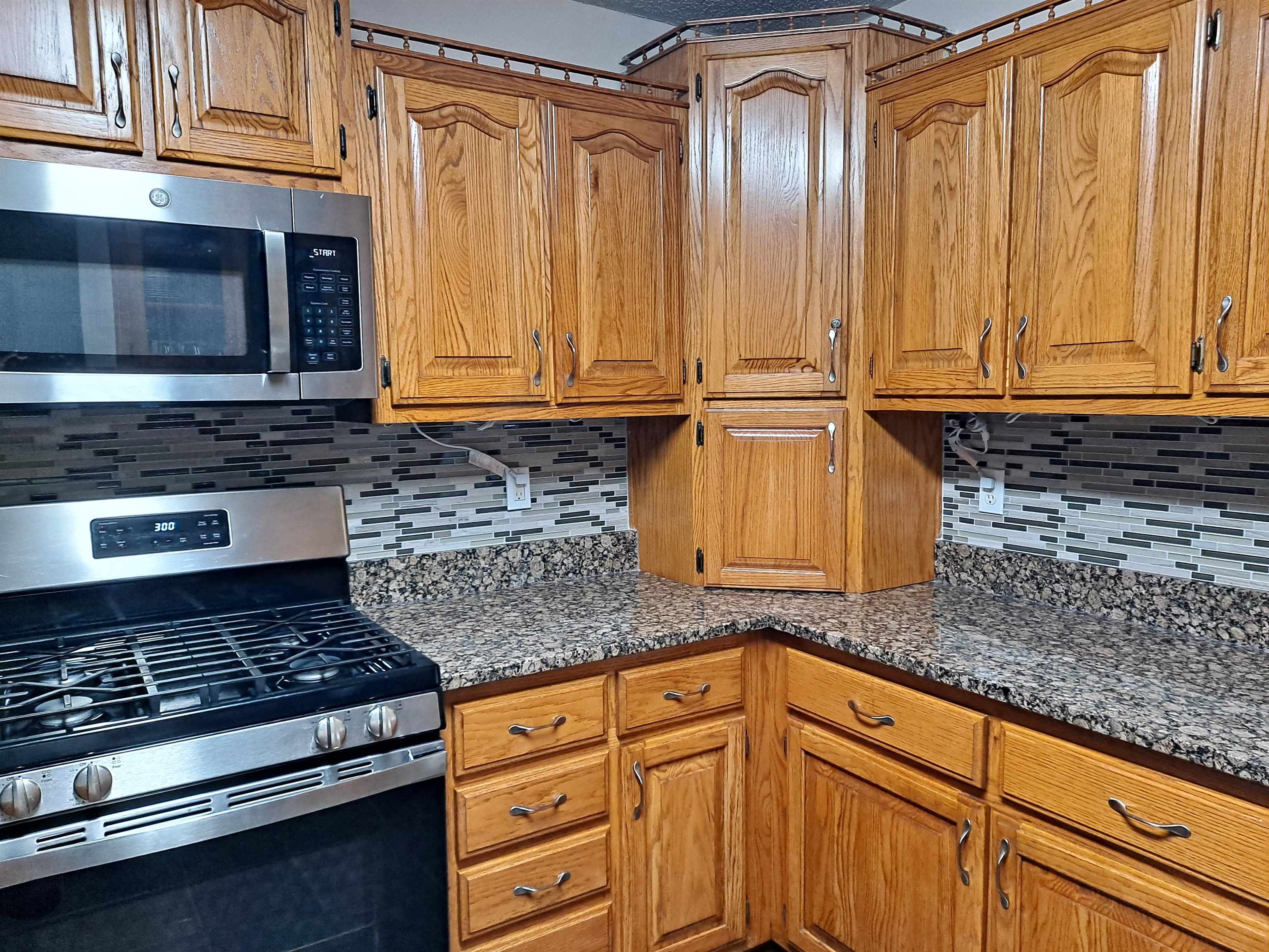 Kitchen with appliances with stainless steel finishes, dark stone counters, and tasteful backsplash