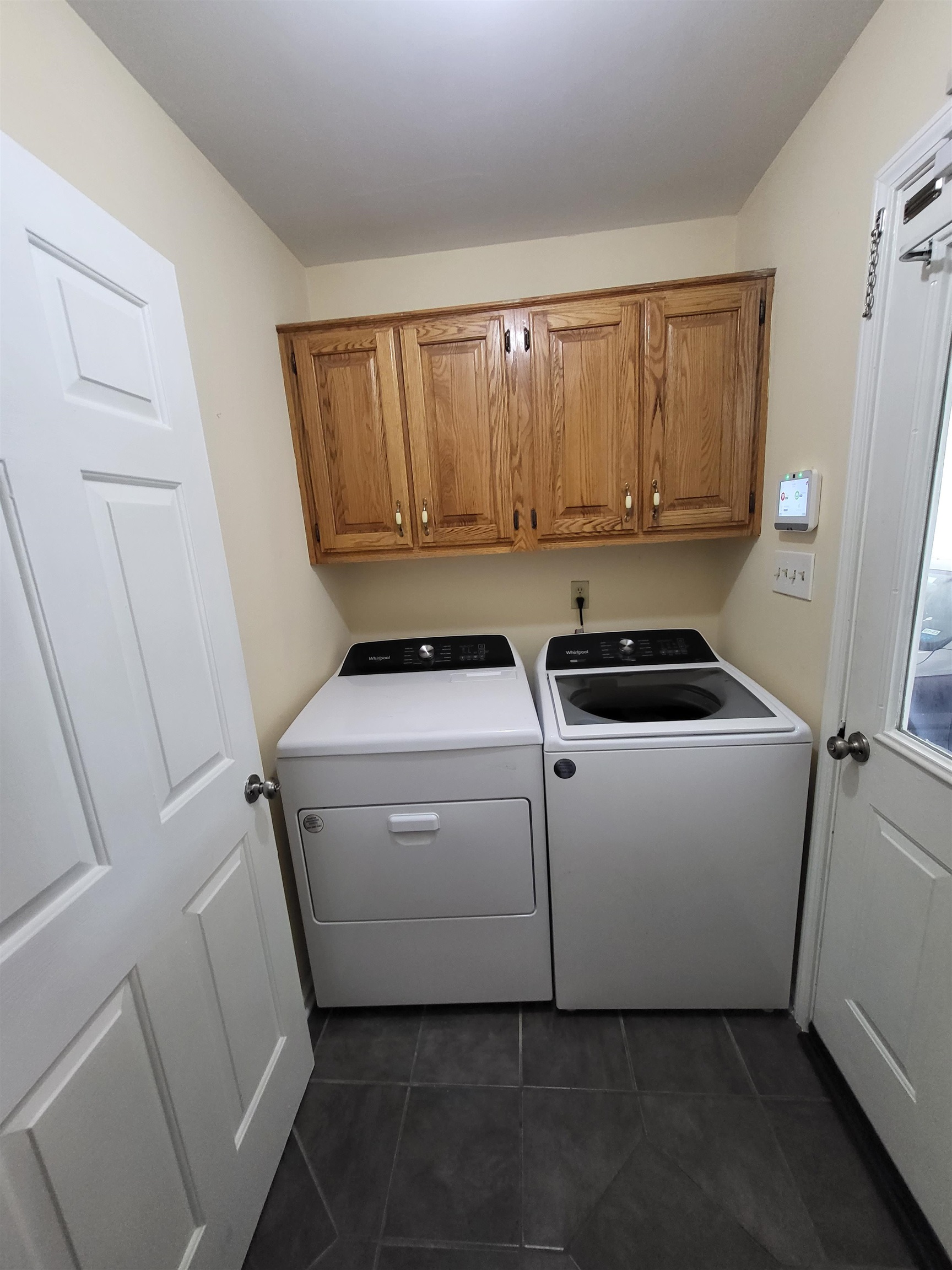 Laundry room featuring dark tile patterned flooring, cabinets, and independent washer and dryer