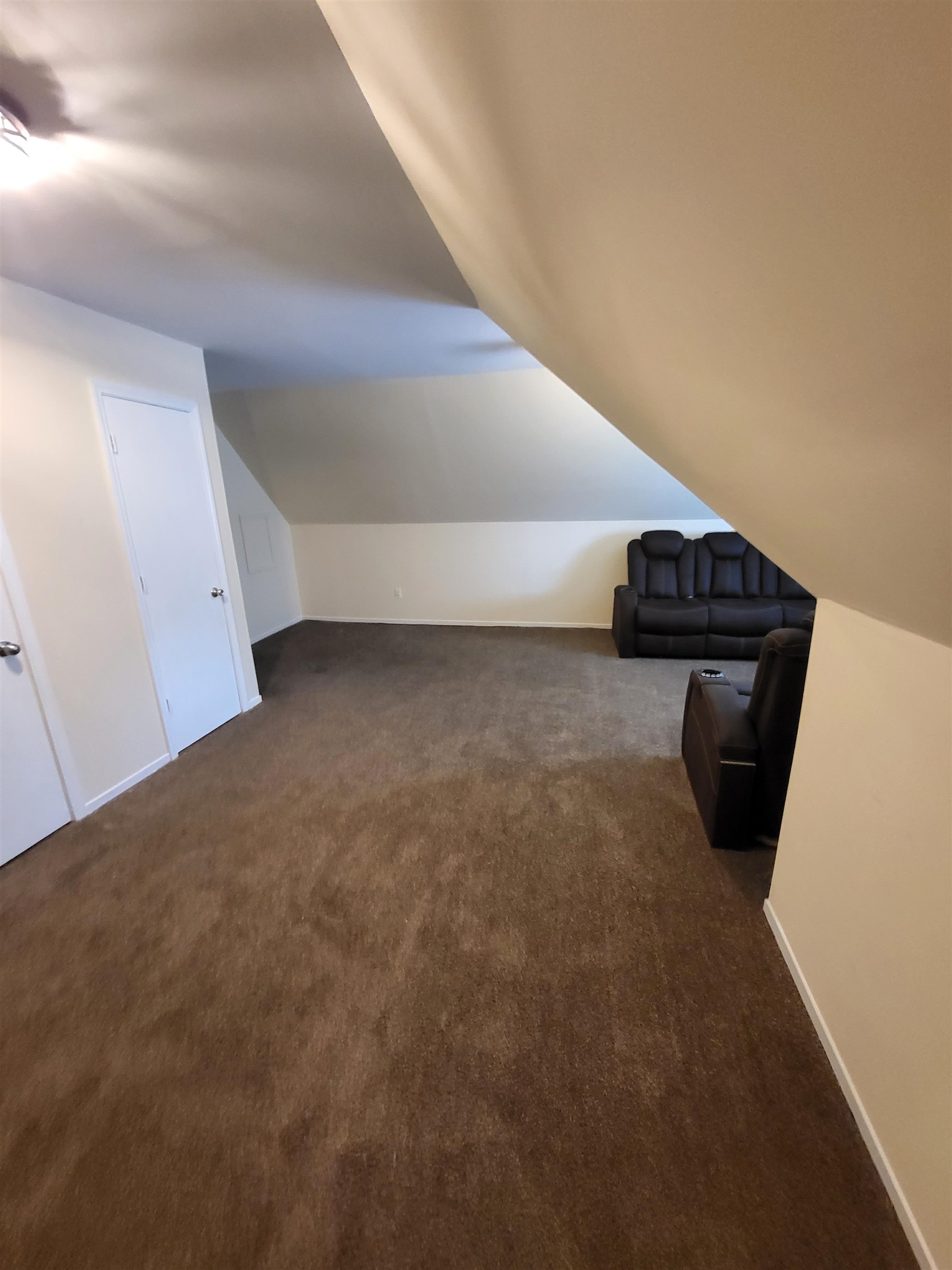 Bonus room with dark colored carpet and vaulted ceiling