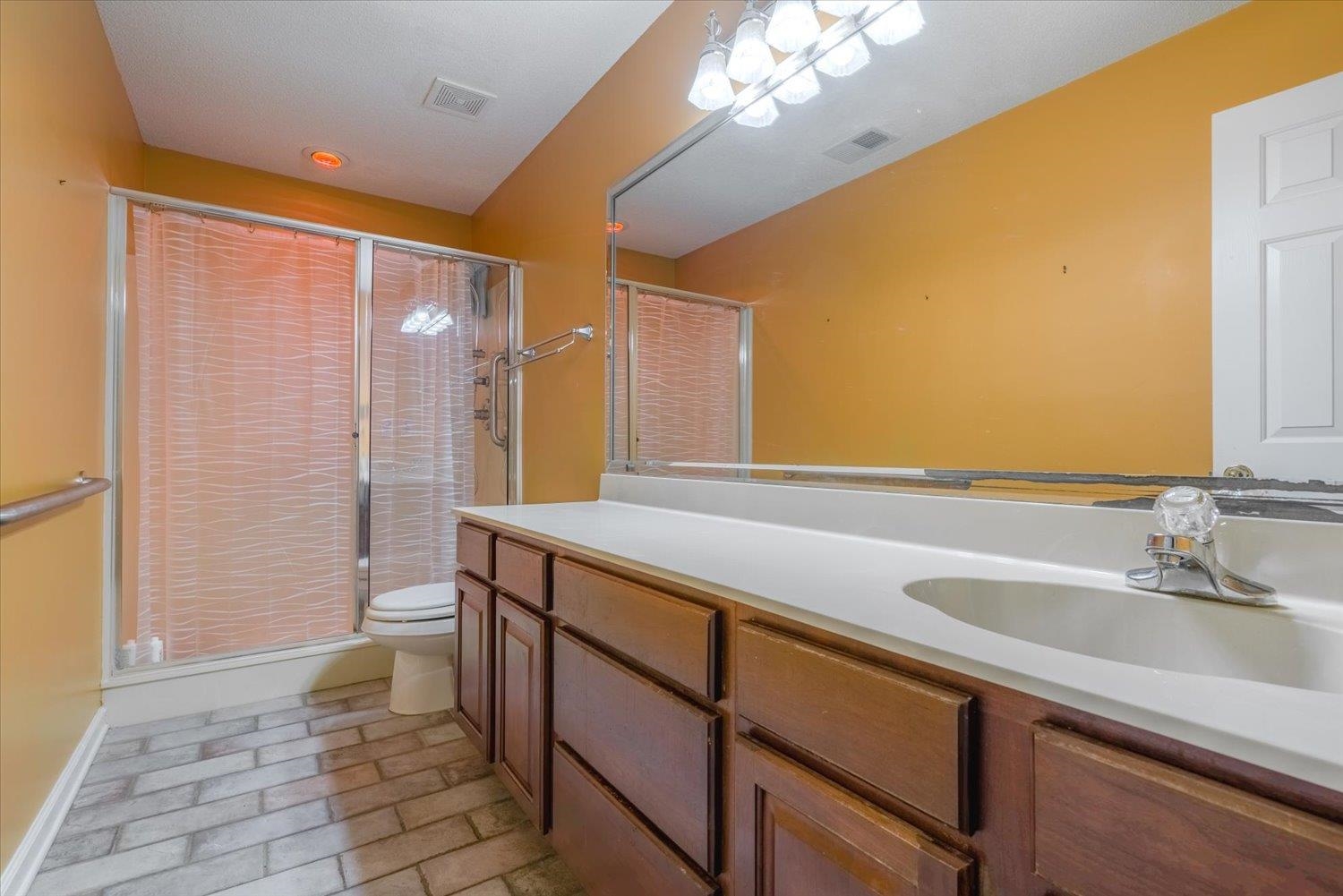 Bathroom with vanity, toilet, and a shower with shower door