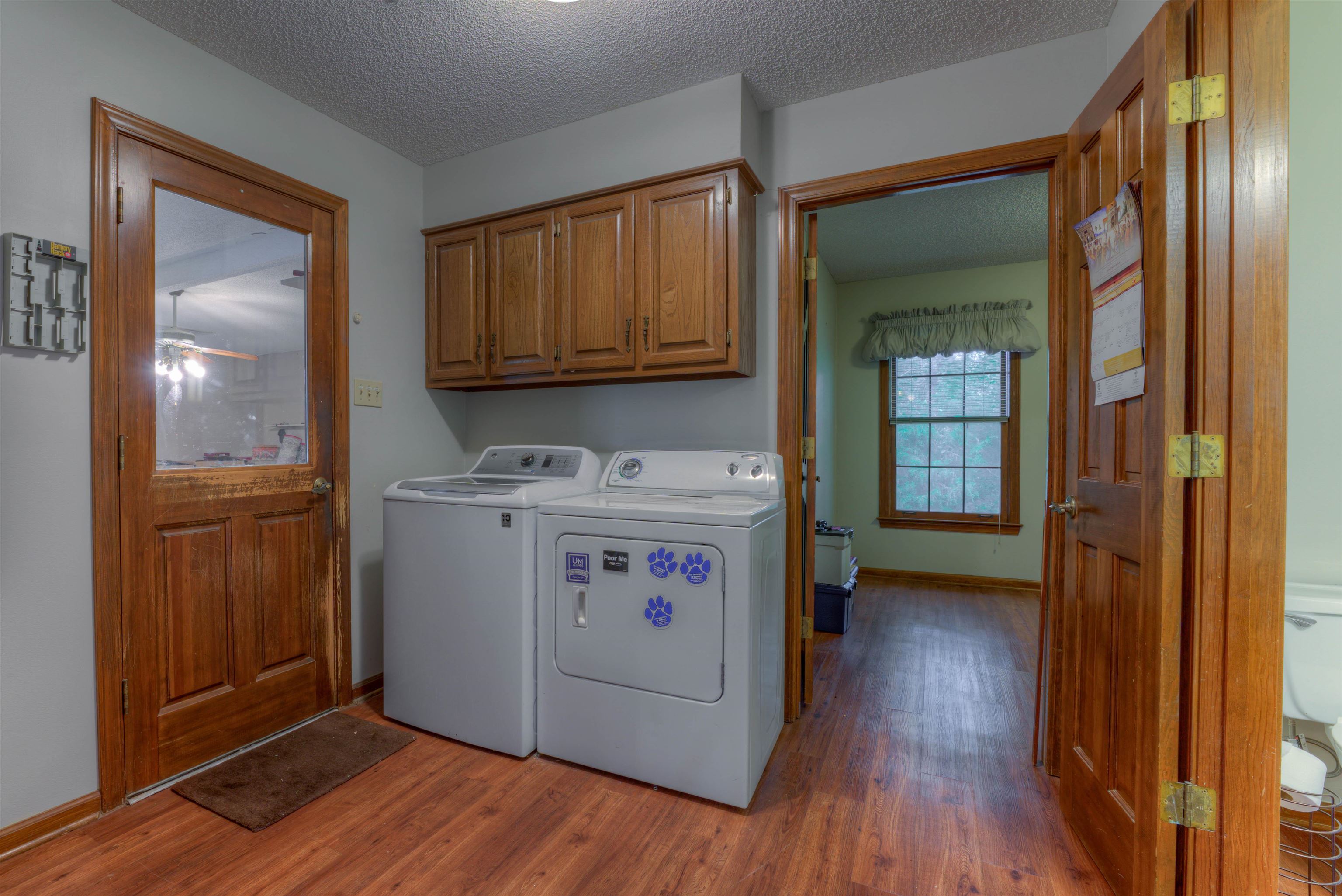 Clothes washing area with cabinets, wood-type flooring, ceiling fan, and independent washer and dryer