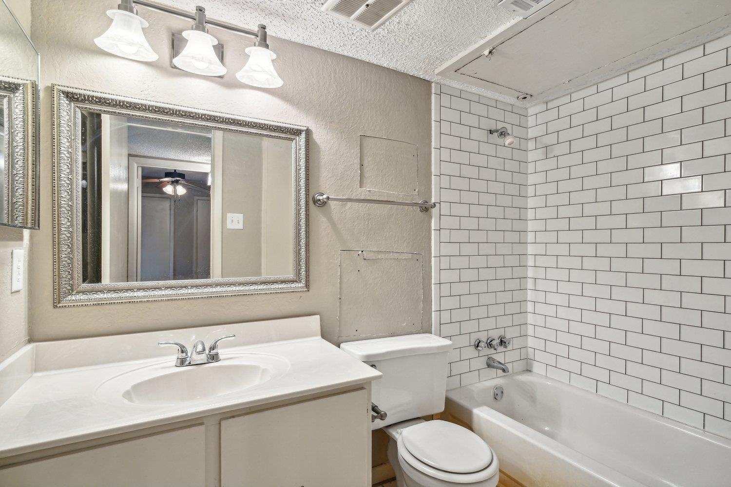 Full bathroom featuring ceiling fan, tiled shower / bath, vanity, a textured ceiling, and toilet