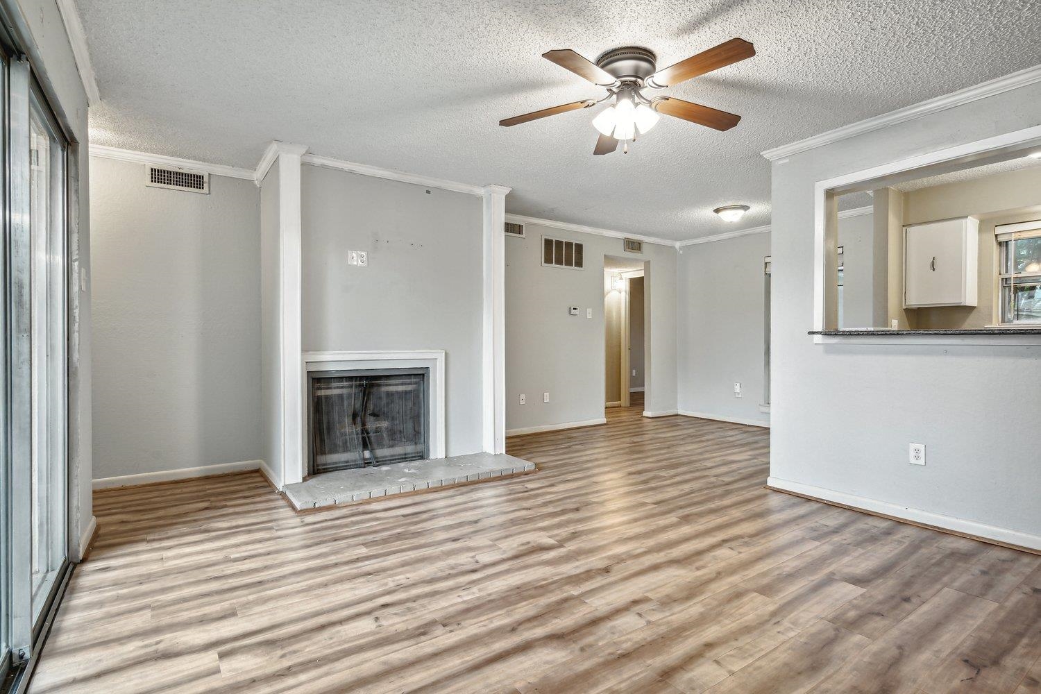 Unfurnished living room with light wood-type flooring, ceiling fan, and a fireplace