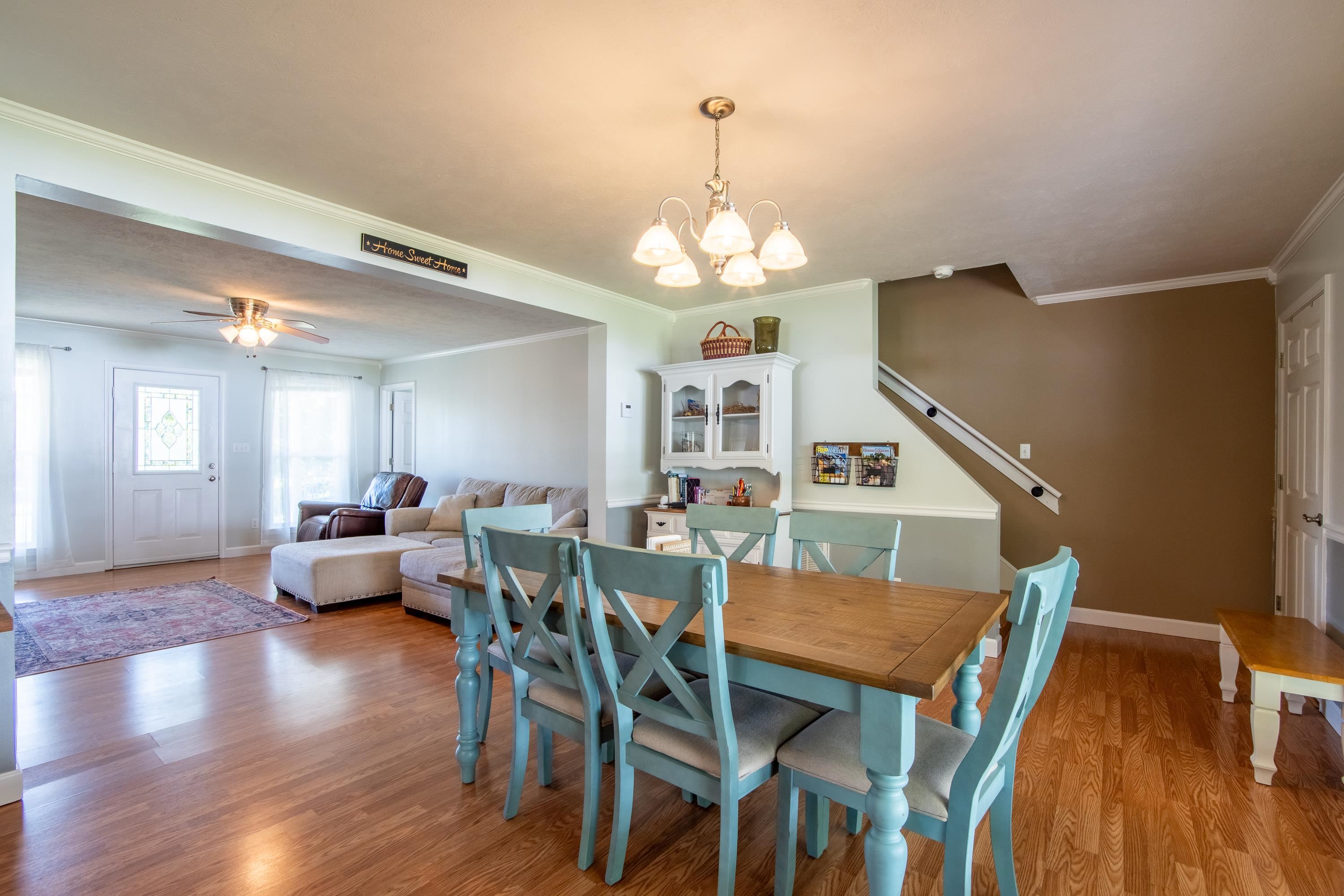 Dining space featuring ornamental molding, ceiling fan with notable chandelier, and light hardwood / wood-style floors