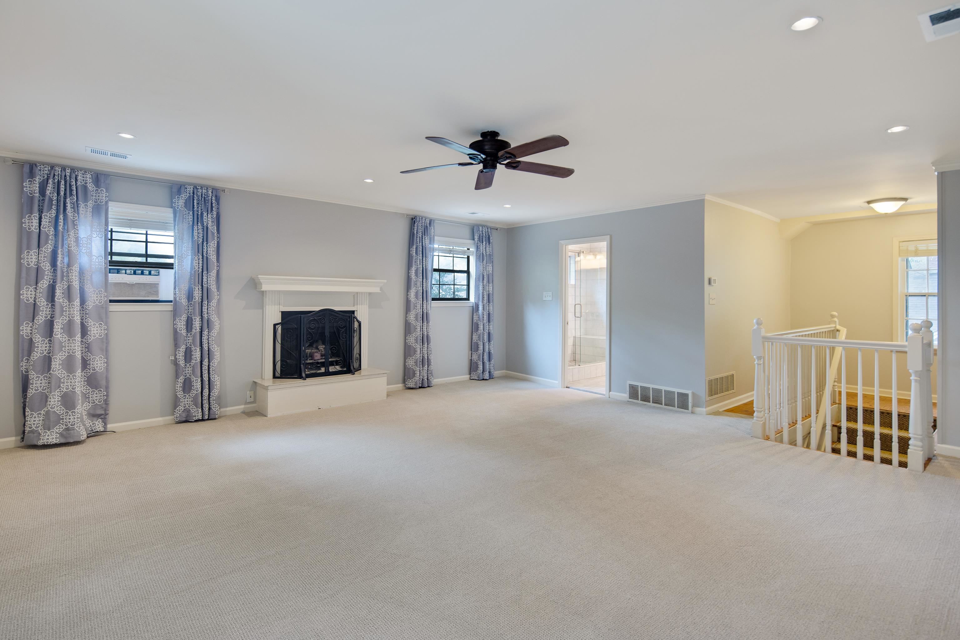 Unfurnished living room with a wealth of natural light, light colored carpet, and ceiling fan