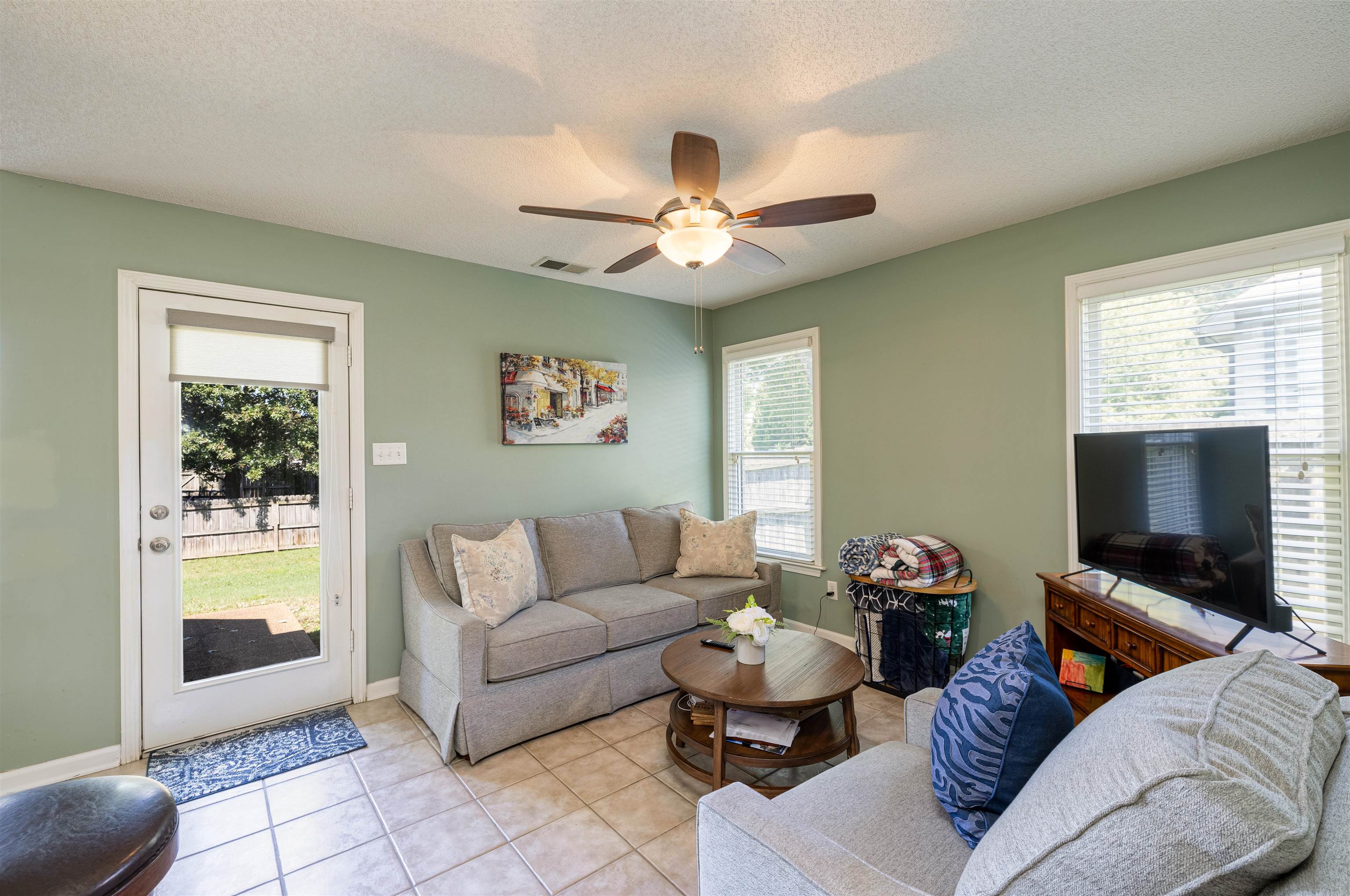 Tiled living room featuring ceiling fan, a textured ceiling, and plenty of natural light