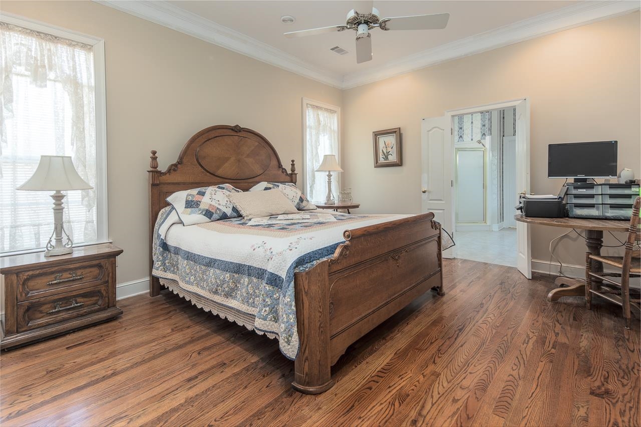 Bedroom featuring ceiling fan, crown molding, dark hardwood / wood-style floors, and multiple windows