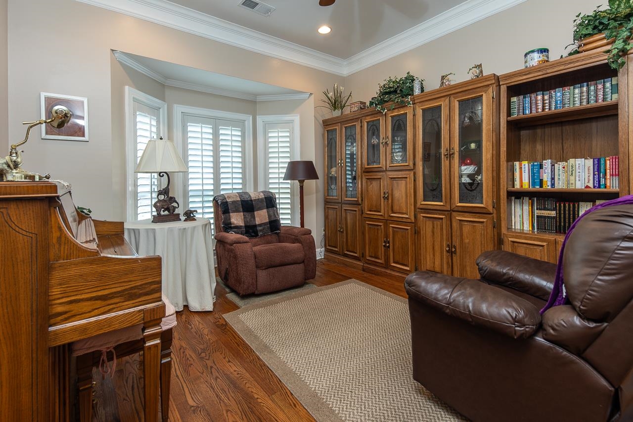 Living room with crown molding, dark hardwood / wood-style floors, and ceiling fan