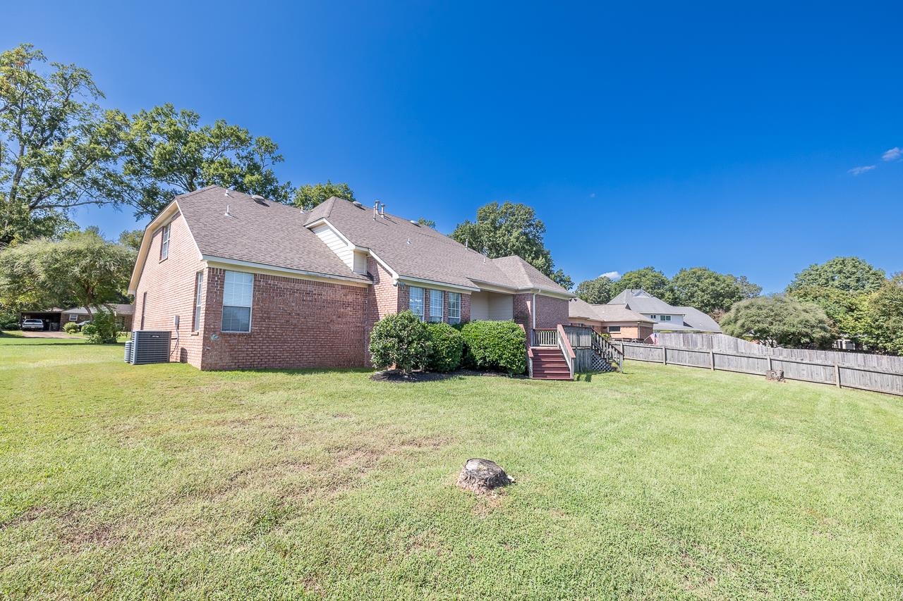 Back of house featuring a yard and central AC