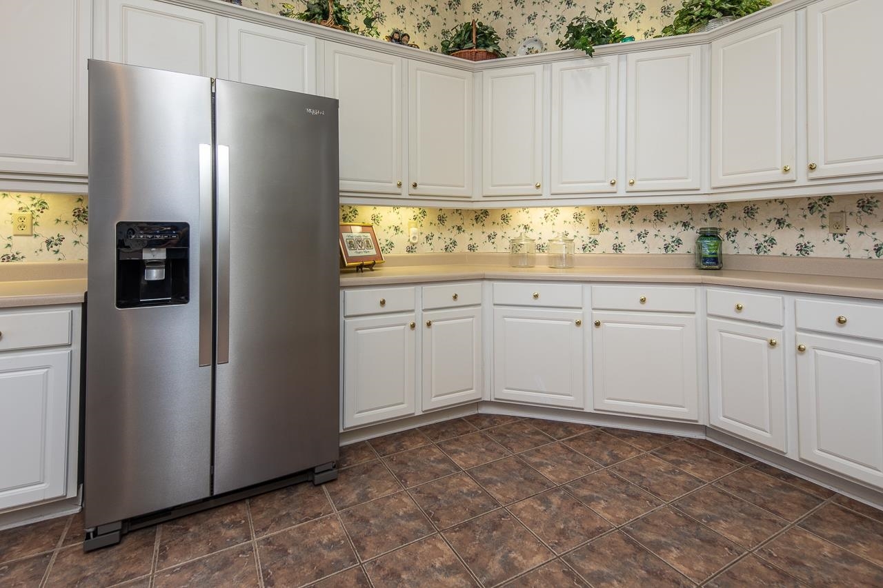 Kitchen with stainless steel refrigerator with ice dispenser and white cabinetry