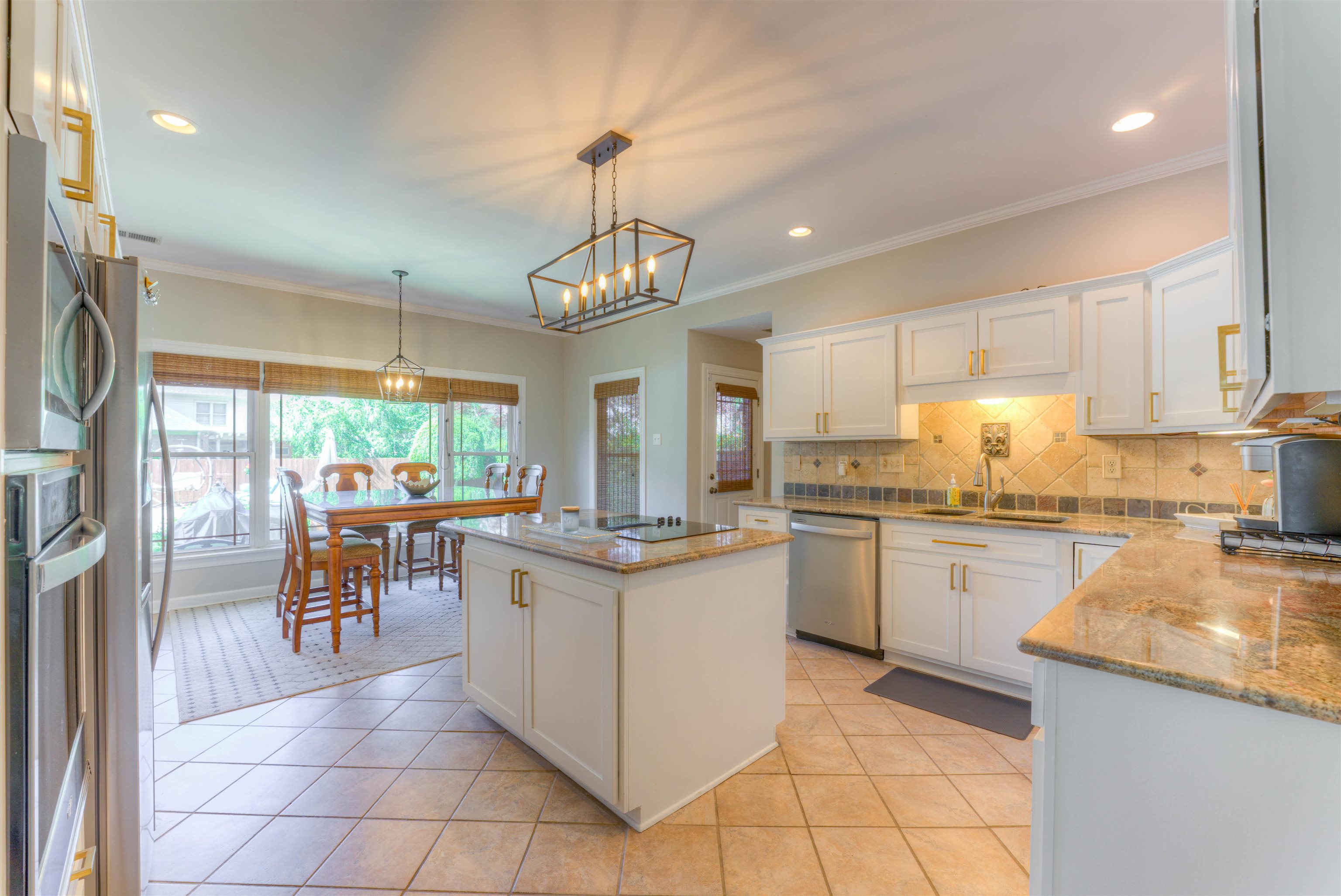 Kitchen featuring white cabinets, pendant lighting, light tile patterned floors, a kitchen island, and appliances with stainless steel finishes